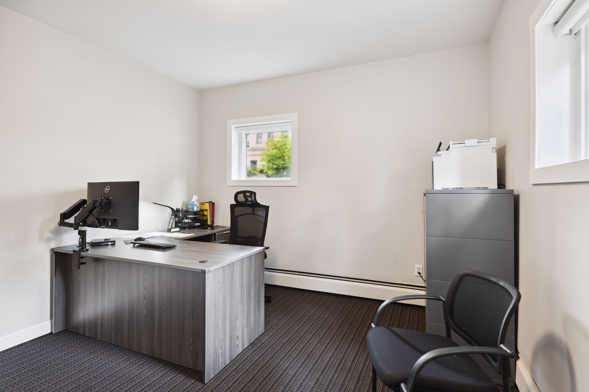 Office from a second angle with an L-shaped desk, a monitor, a task chair and a filing cabinet