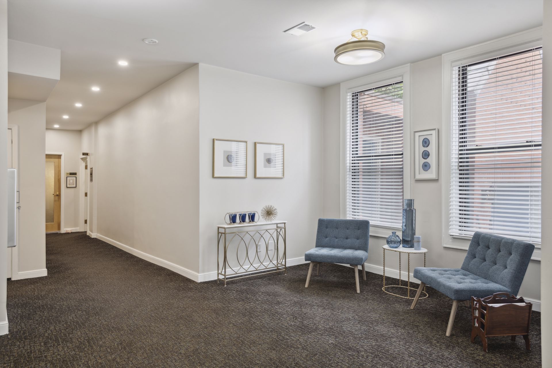 Corridor looking toward a seating nook with teal tufted chairs