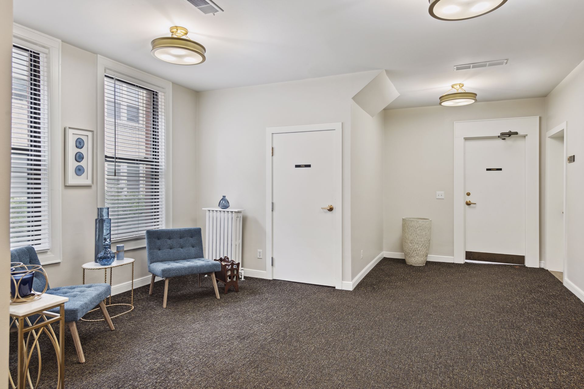 Upper-floor landing with two white suite doors, a pair of teal chairs, a radiator and flush-mounted ceiling fixtures