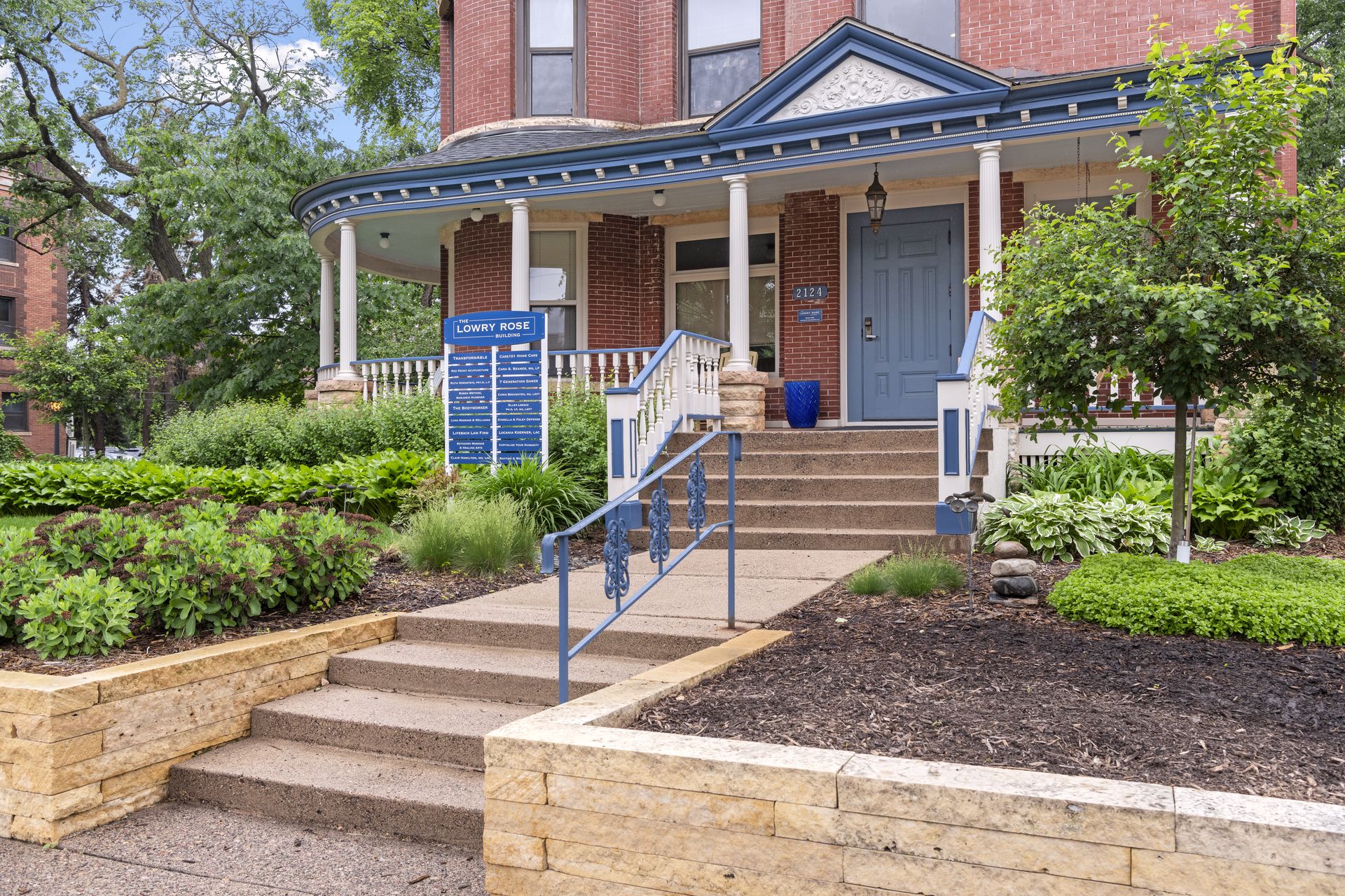 Limestone front steps with blue ornamental iron railings leading to the blue front door of the Lowry Rose Building