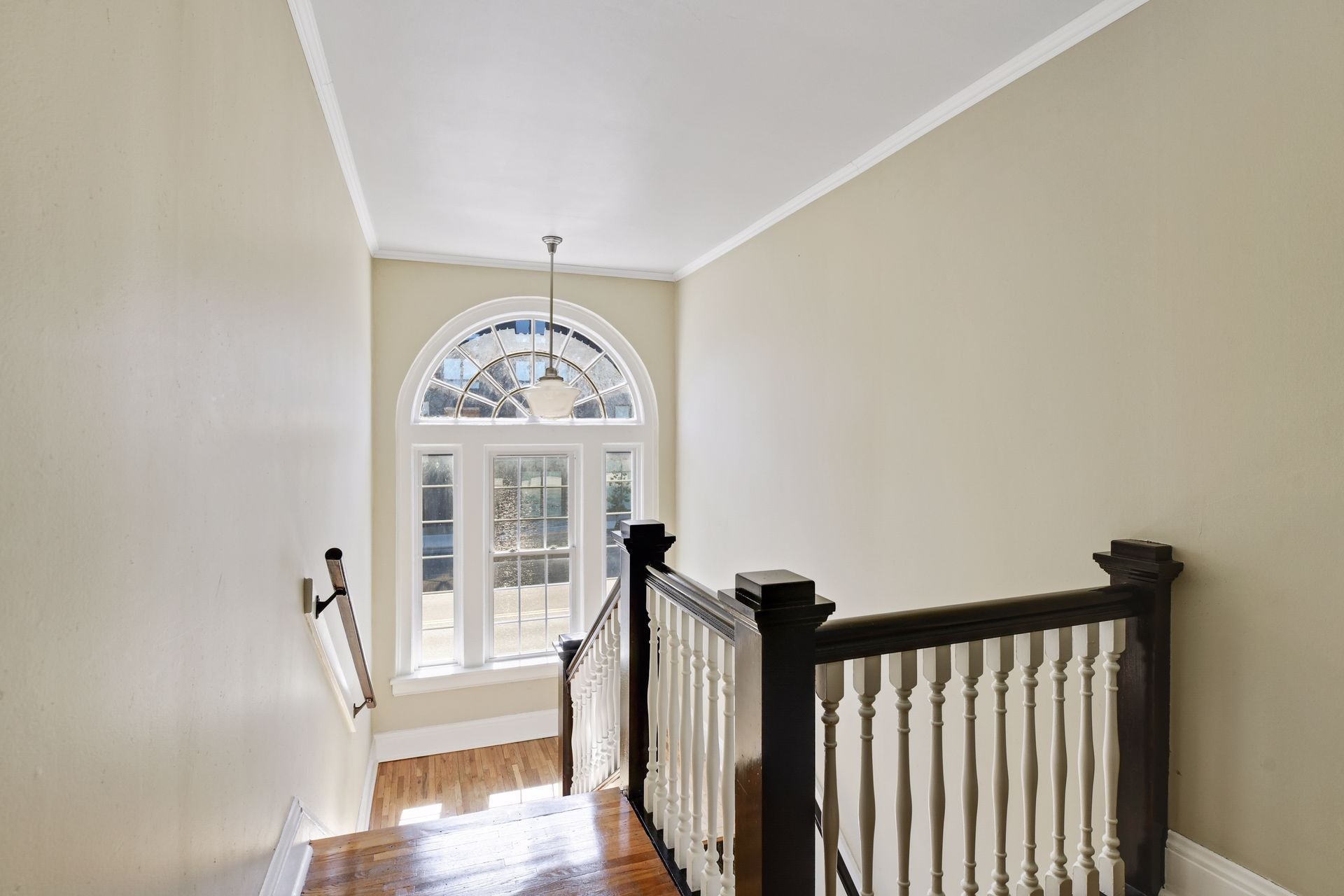 Upper stair hall with a dark wood balustrade and a large arched fanlight window