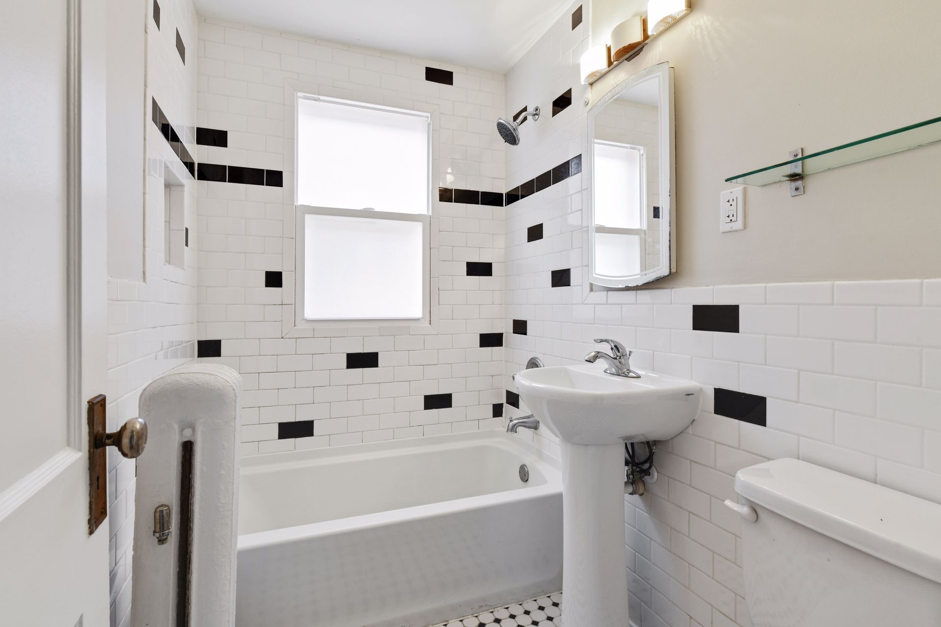Bathroom with white subway tile and black accent tiles, a pedestal sink, an alcove bathtub and a mirrored medicine cabinet
