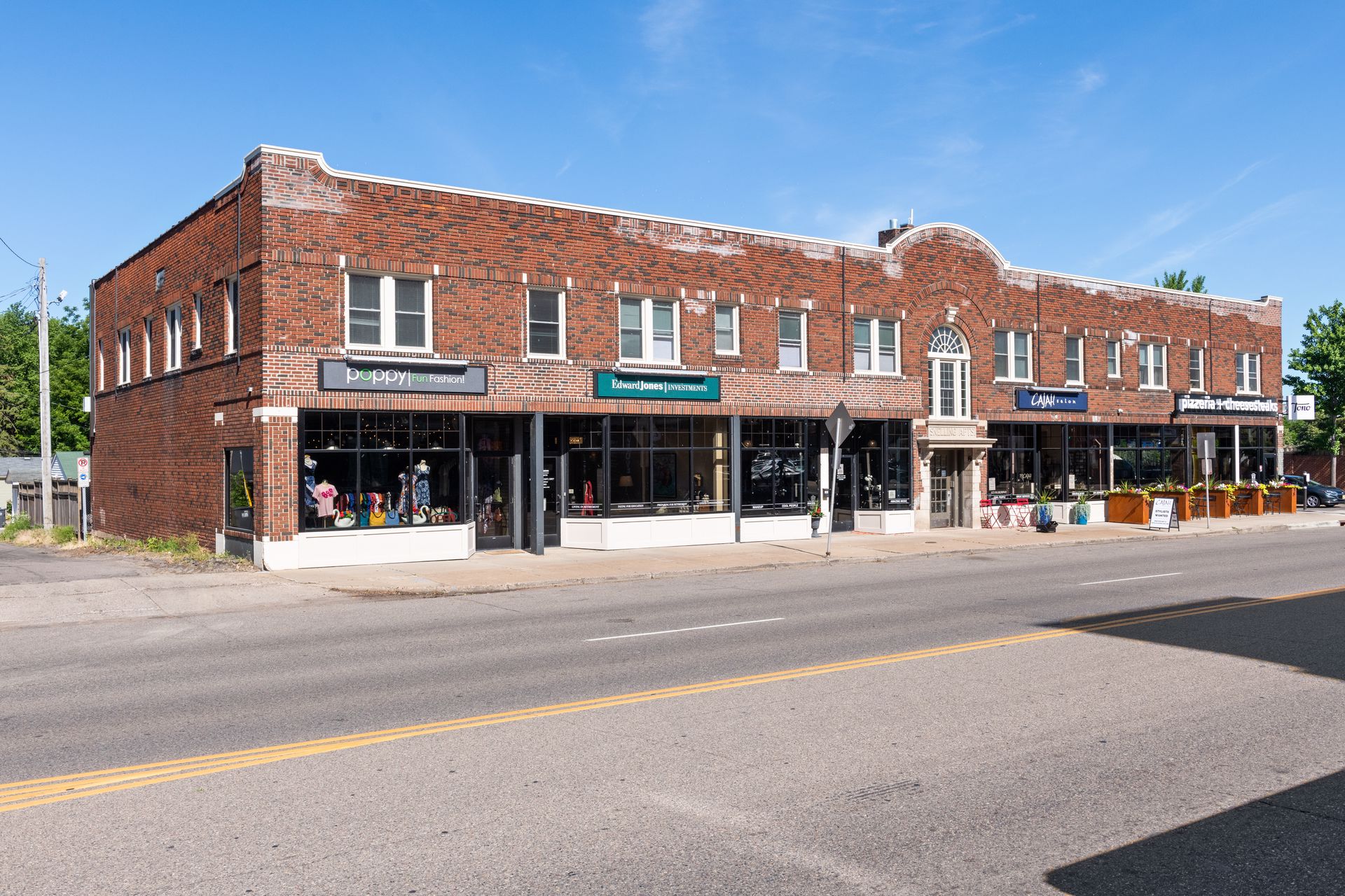 Street elevation of the two-storey brick building with four ground-floor storefronts and an arched central entrance