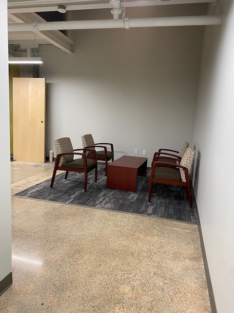Small seating nook with four side chairs around a dark coffee table on a patterned rug