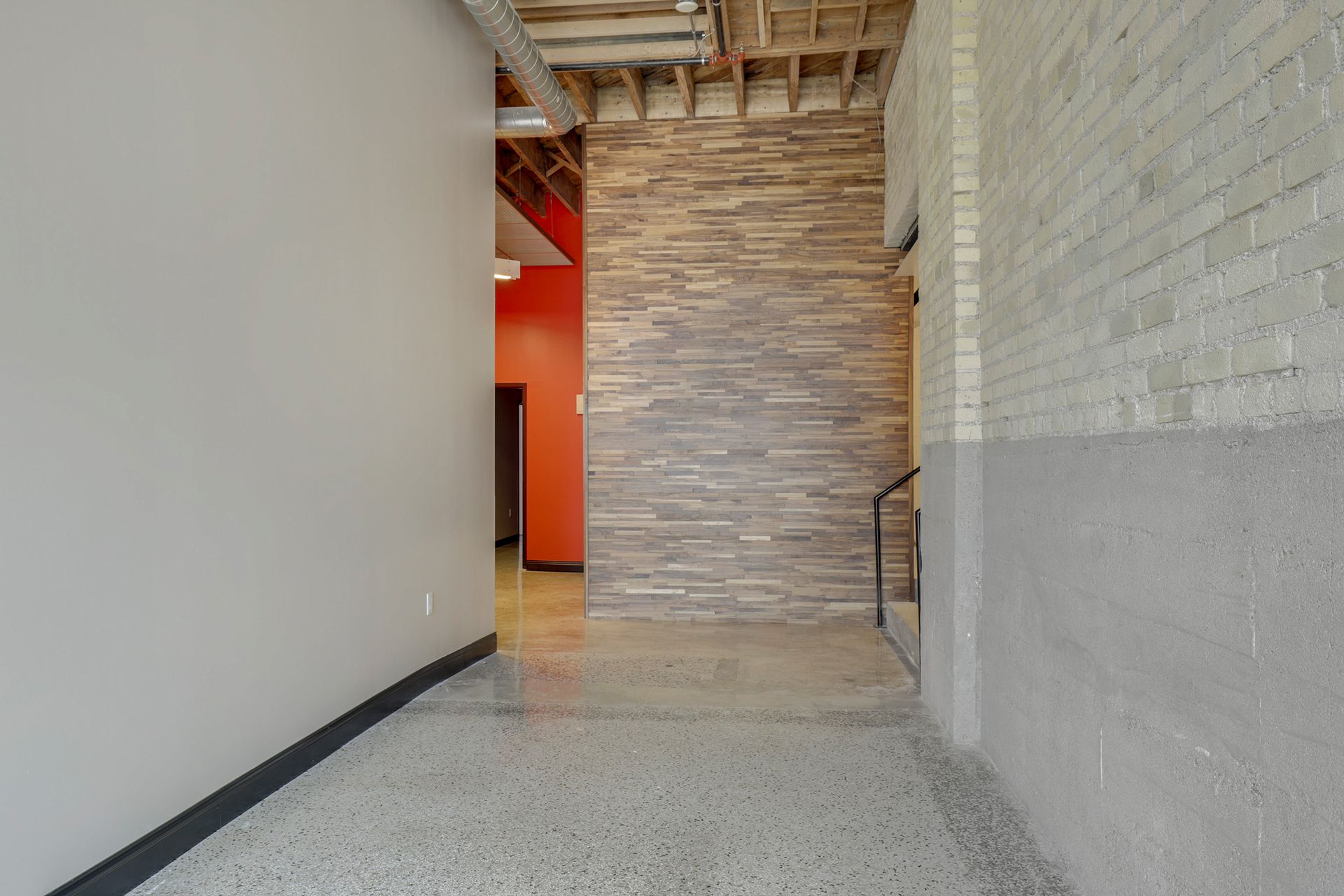 Lobby corner with a stacked stone feature wall, exposed brick and an orange painted wall beyond