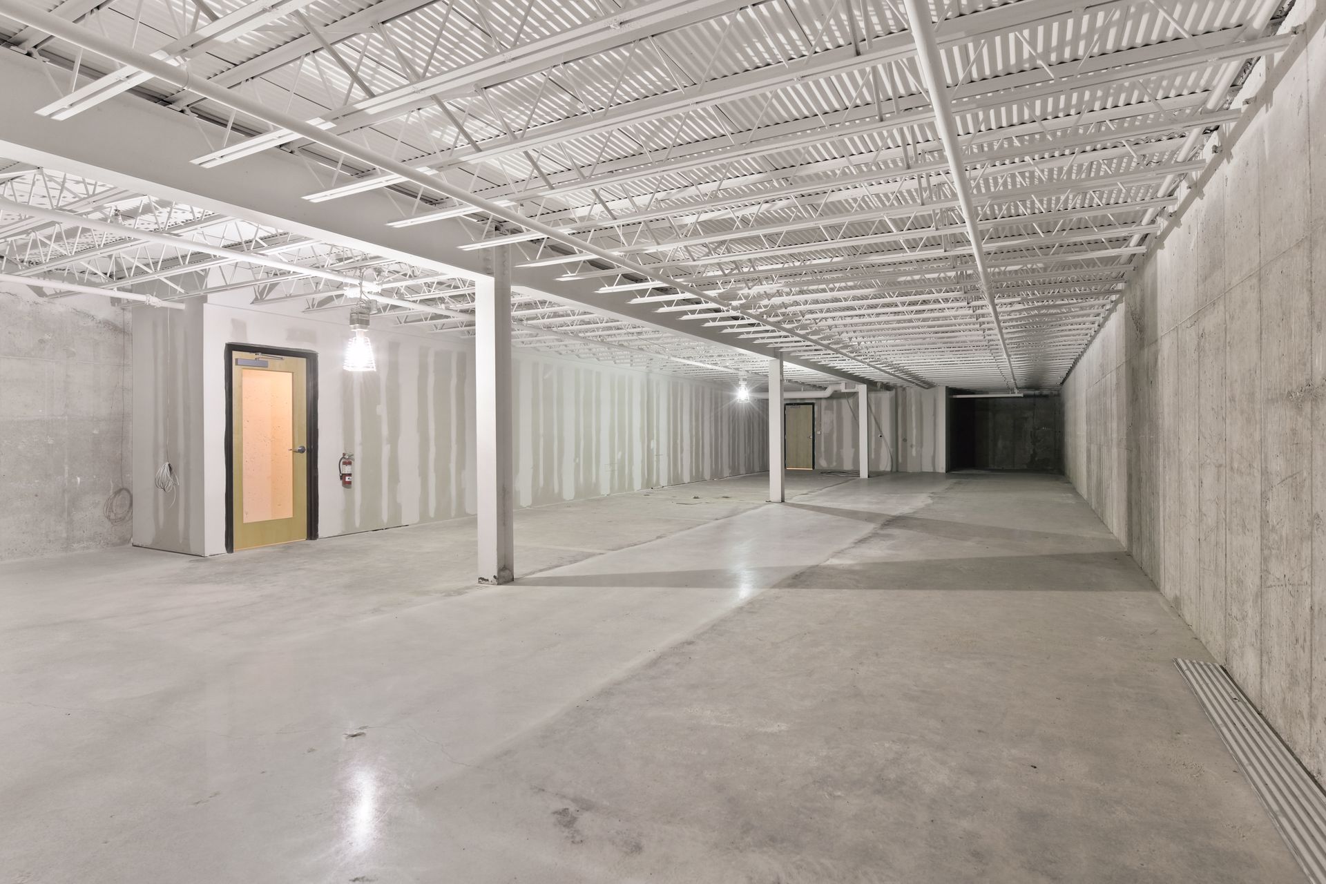 Lower level during construction, with exposed steel bar joists and cast concrete walls