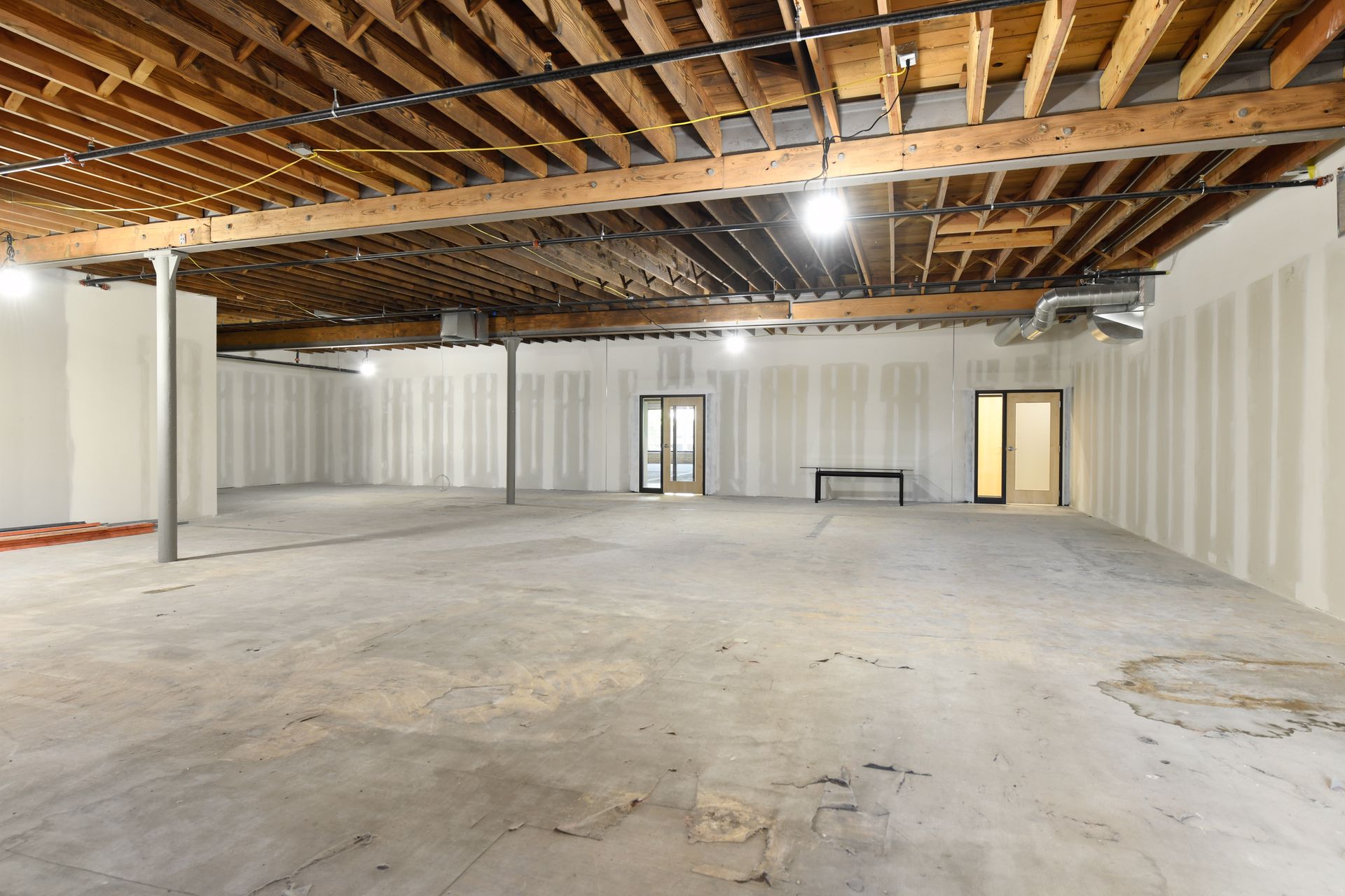 Empty floor with exposed joists and newly built drywall partitions and doors