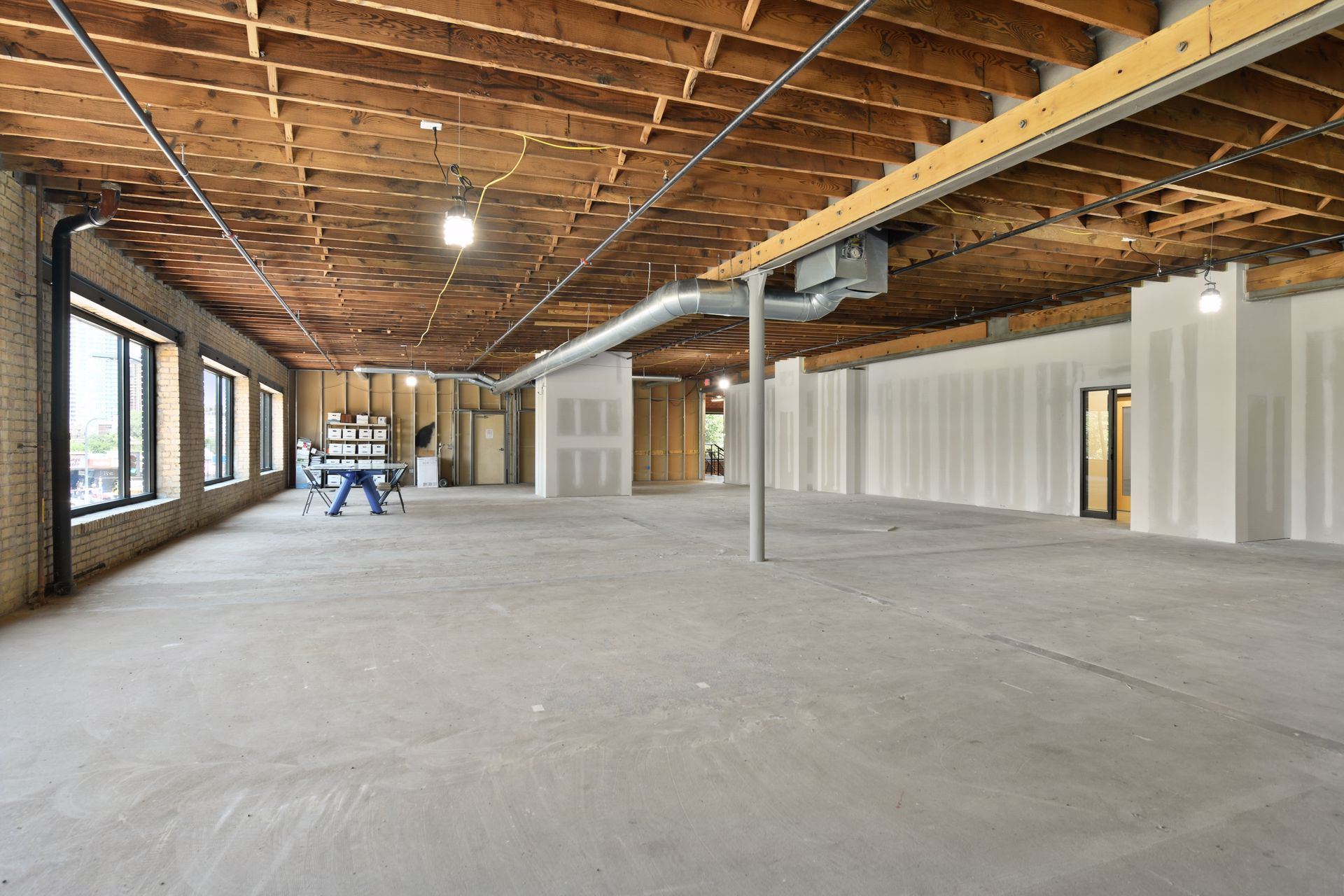 Cream brick wall with a band of windows beneath an exposed wood joist ceiling