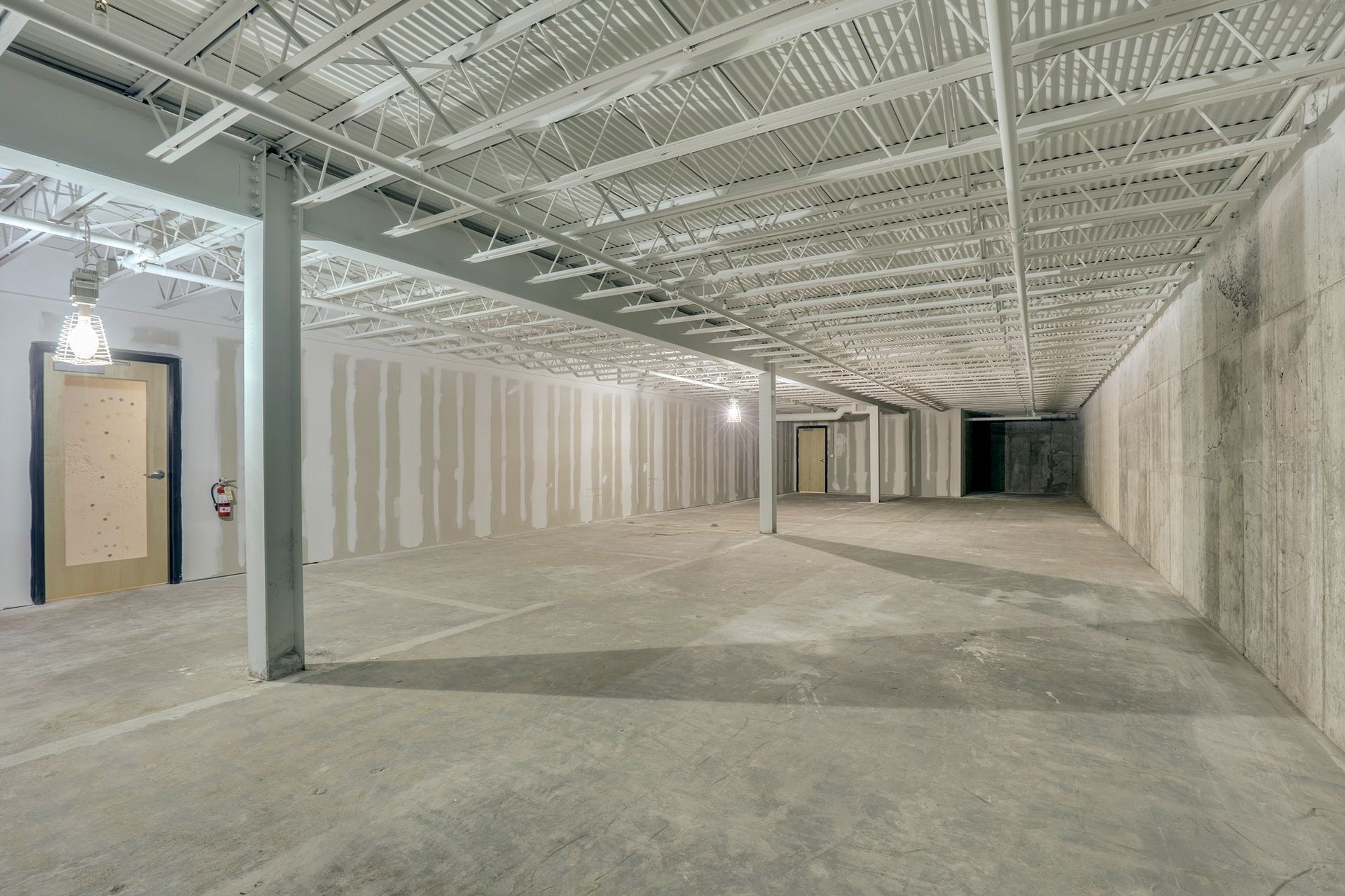 Lower level with exposed steel bar joists and cast concrete walls
