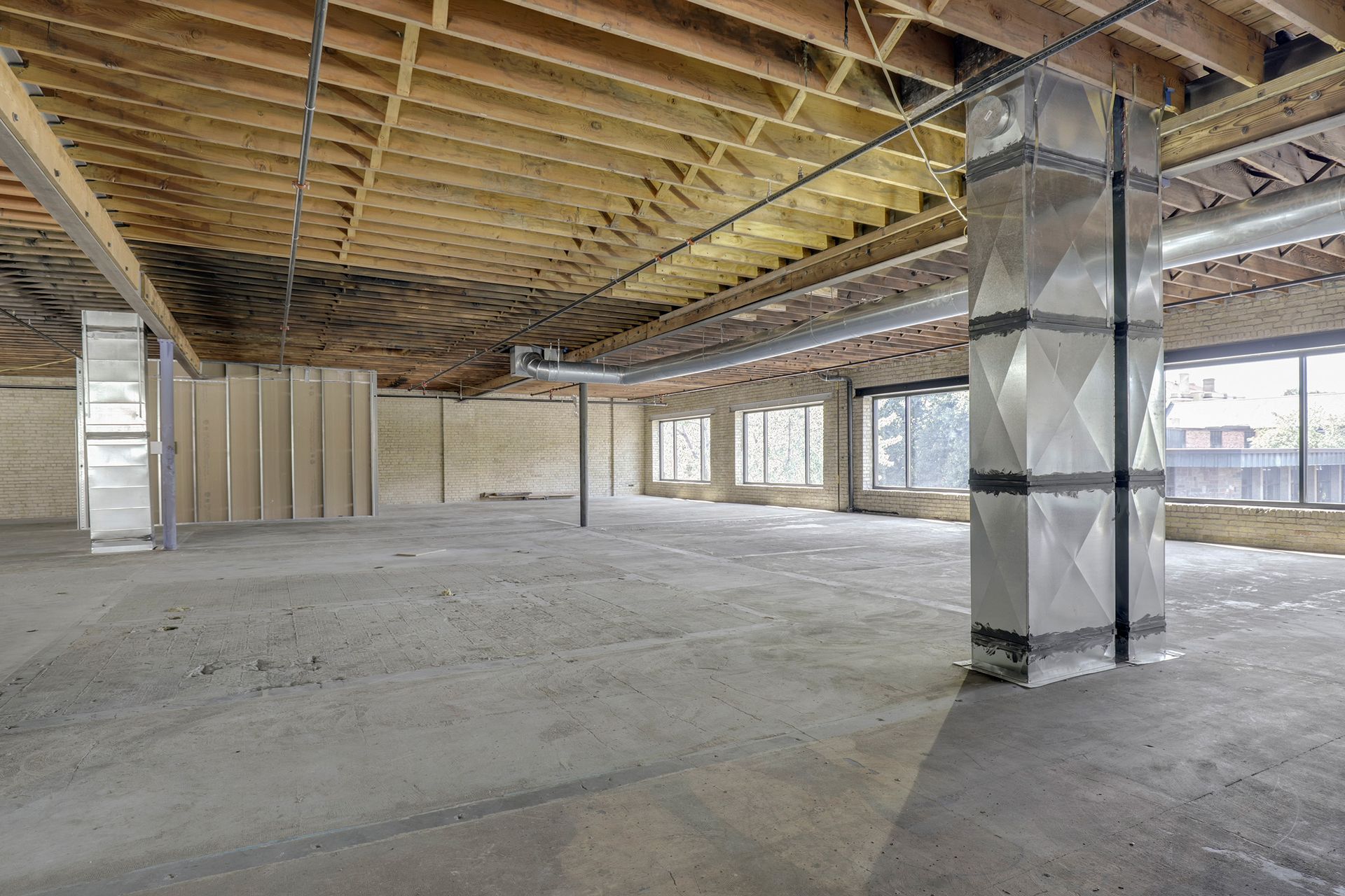 Empty floor plate with a foil-wrapped duct shaft rising through the middle of the space