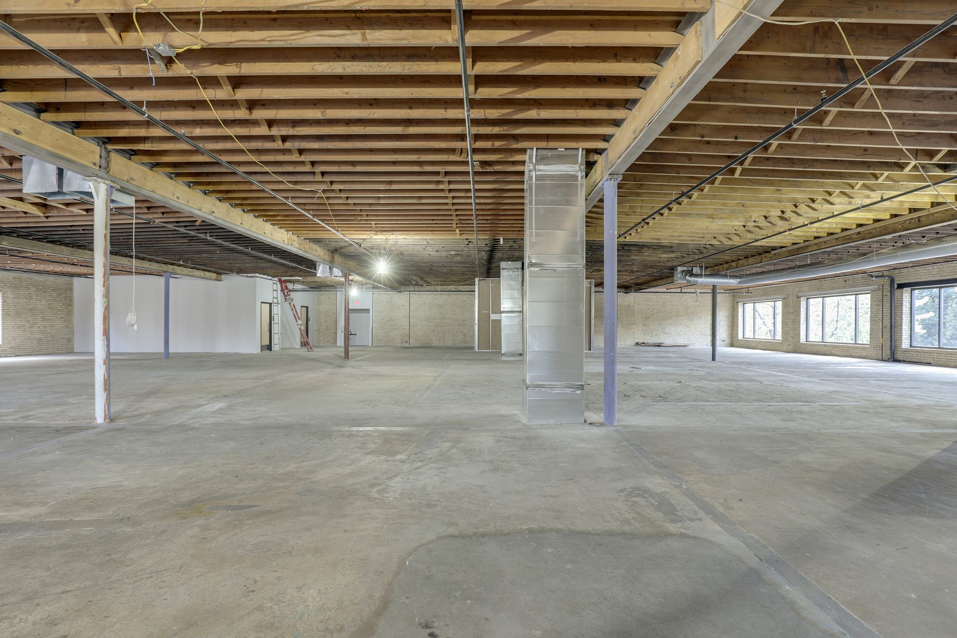 Large empty floor plate with exposed wood joists, steel columns and overhead ductwork