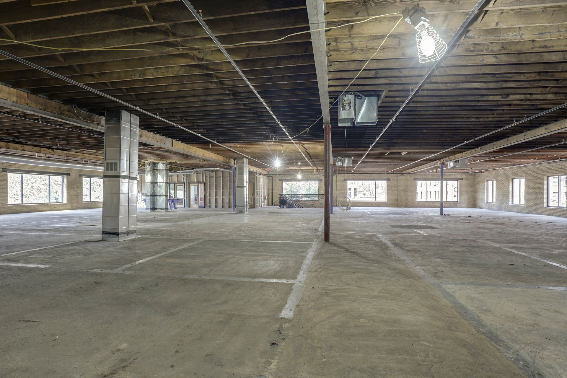 Empty floor plate with exposed wood joists and brick piers