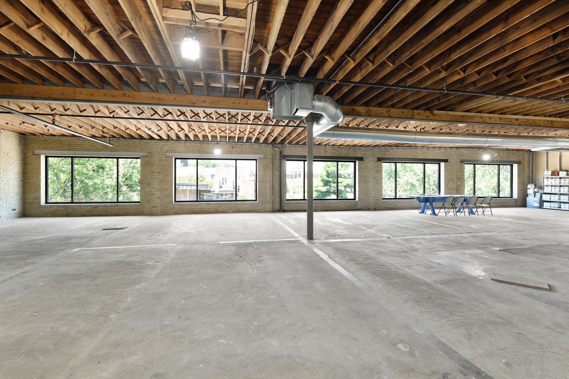 Open upper floor with exposed wood joists, cream brick walls and a continuous band of windows