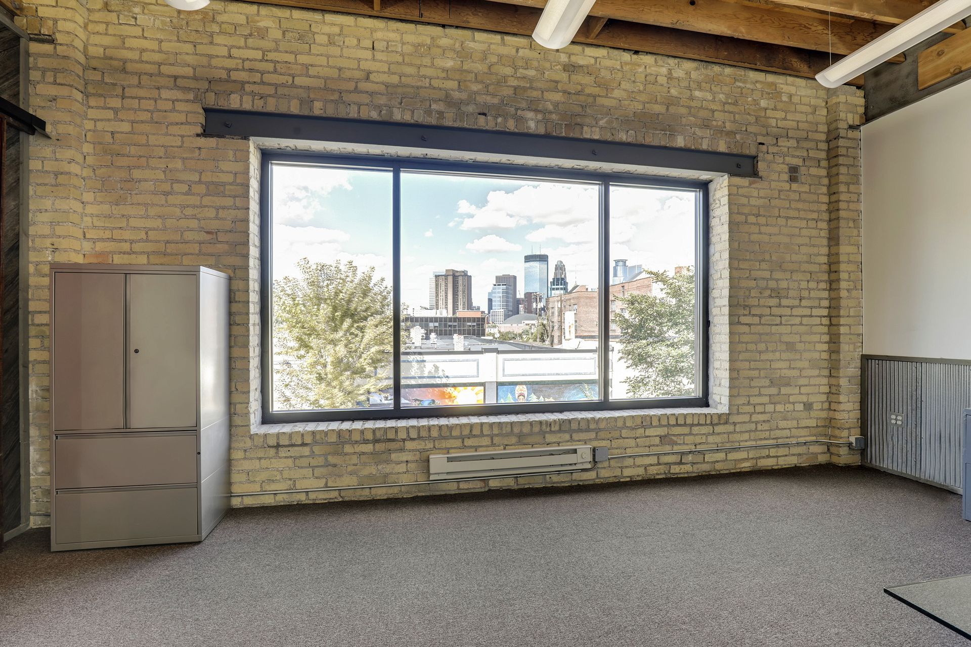 Office window set in a cream brick wall framing a view of the downtown Minneapolis skyline