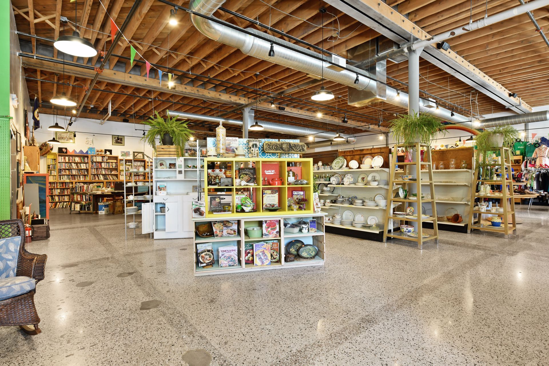 Ground floor retail space in use, with open shelving of homewares, hanging plants, exposed wood ceiling and terrazzo floor