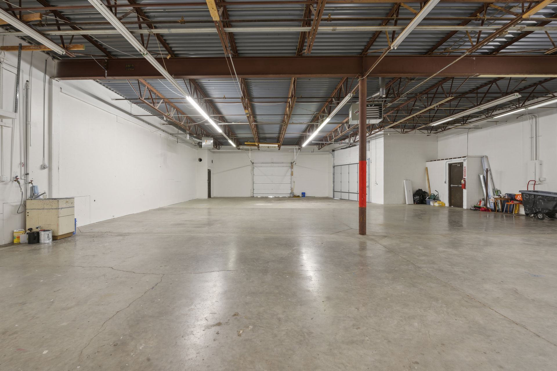 Warehouse bay with painted steel columns, an overhead door and exposed roof structure