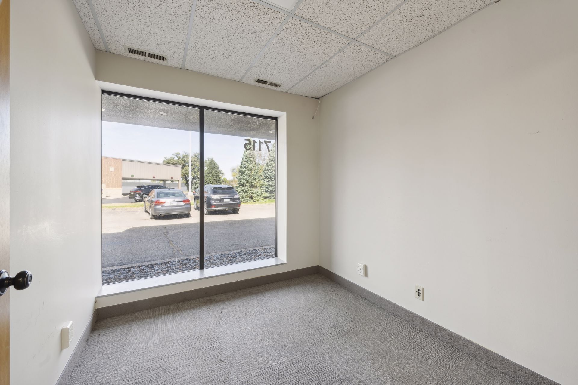 Small office with a large picture window overlooking the parking lot and adjacent building