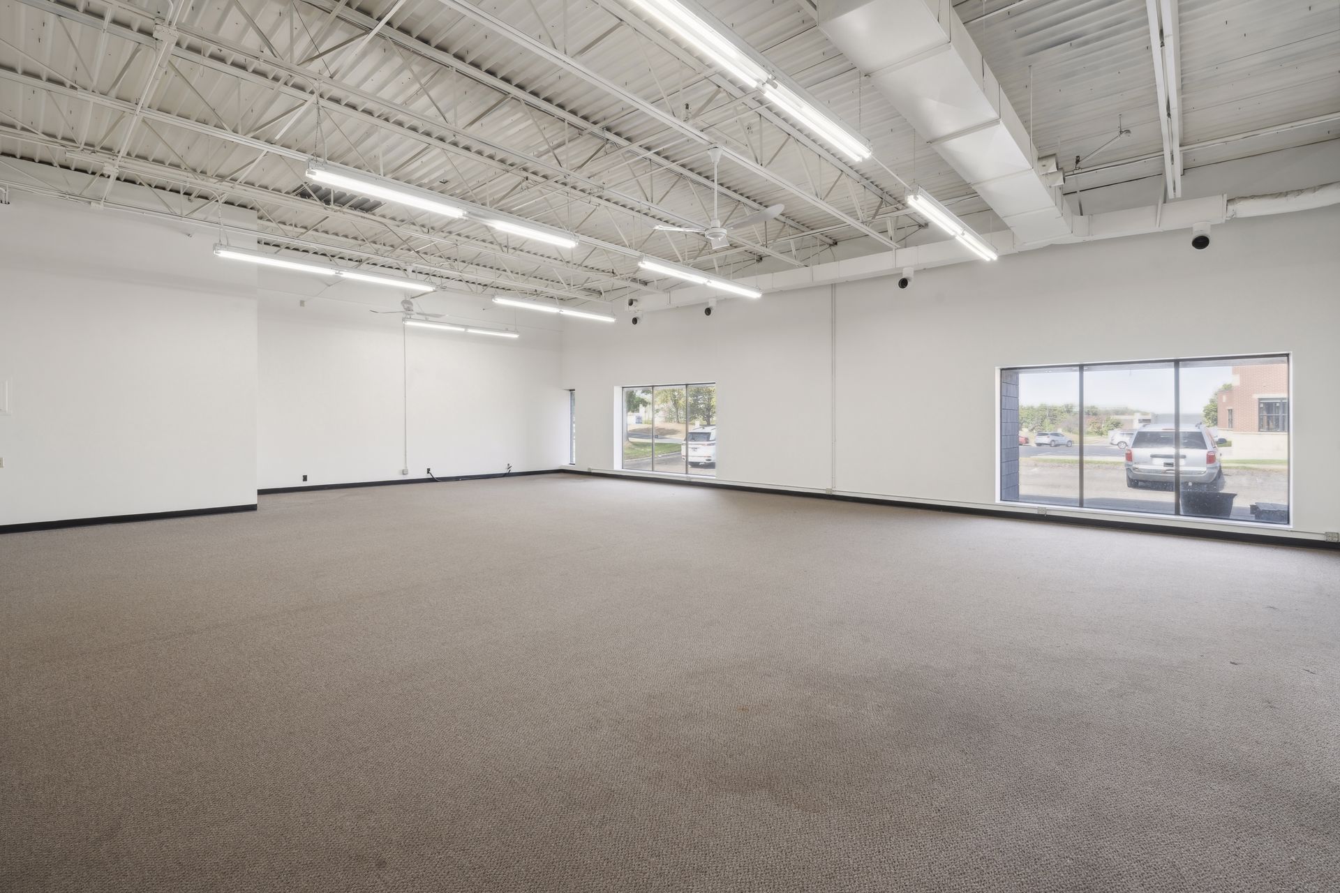 Large open carpeted suite with two windows overlooking the parking lot
