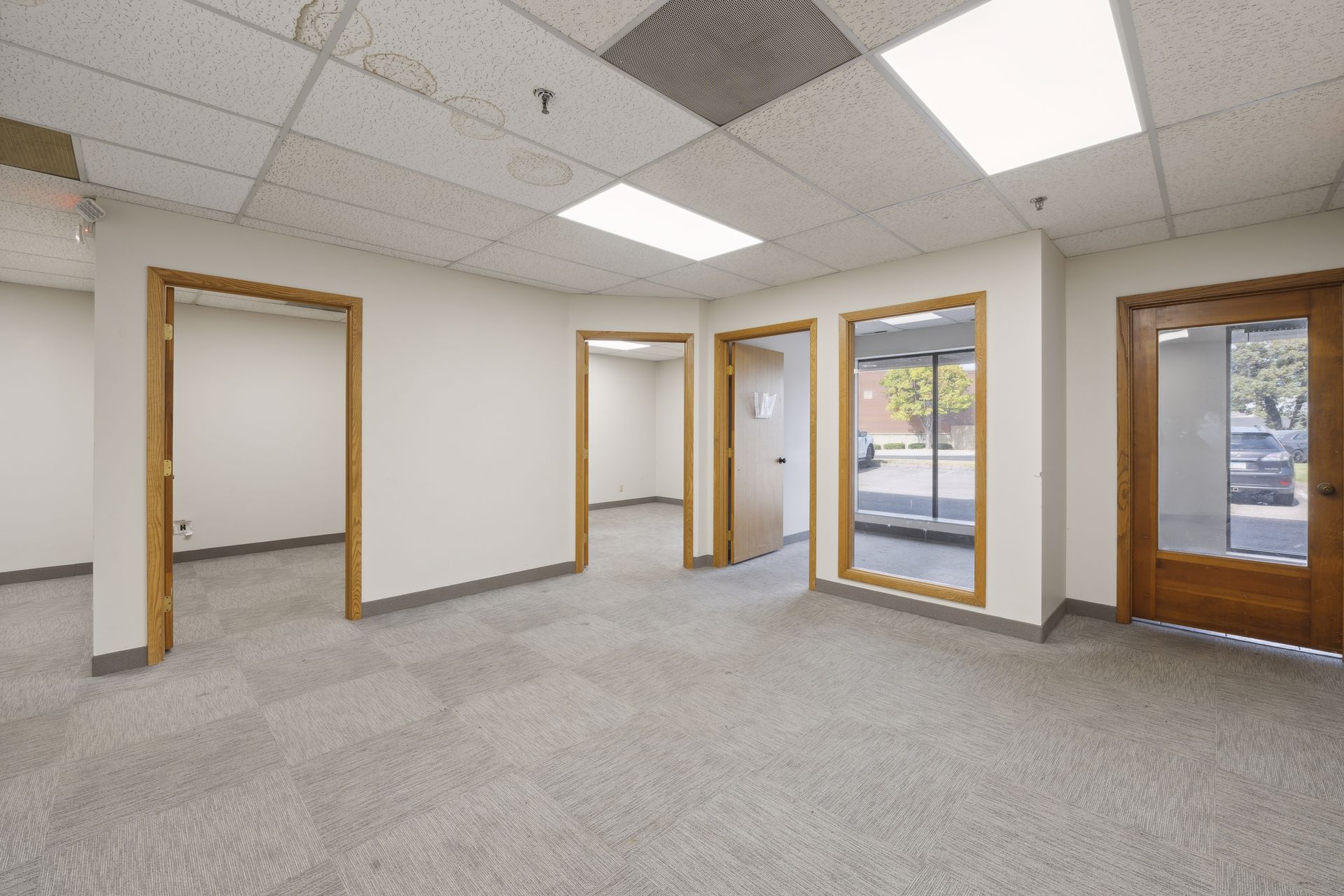 Office suite with a suspended tile ceiling, wood-trimmed doorways and a glazed entrance door onto the parking lot