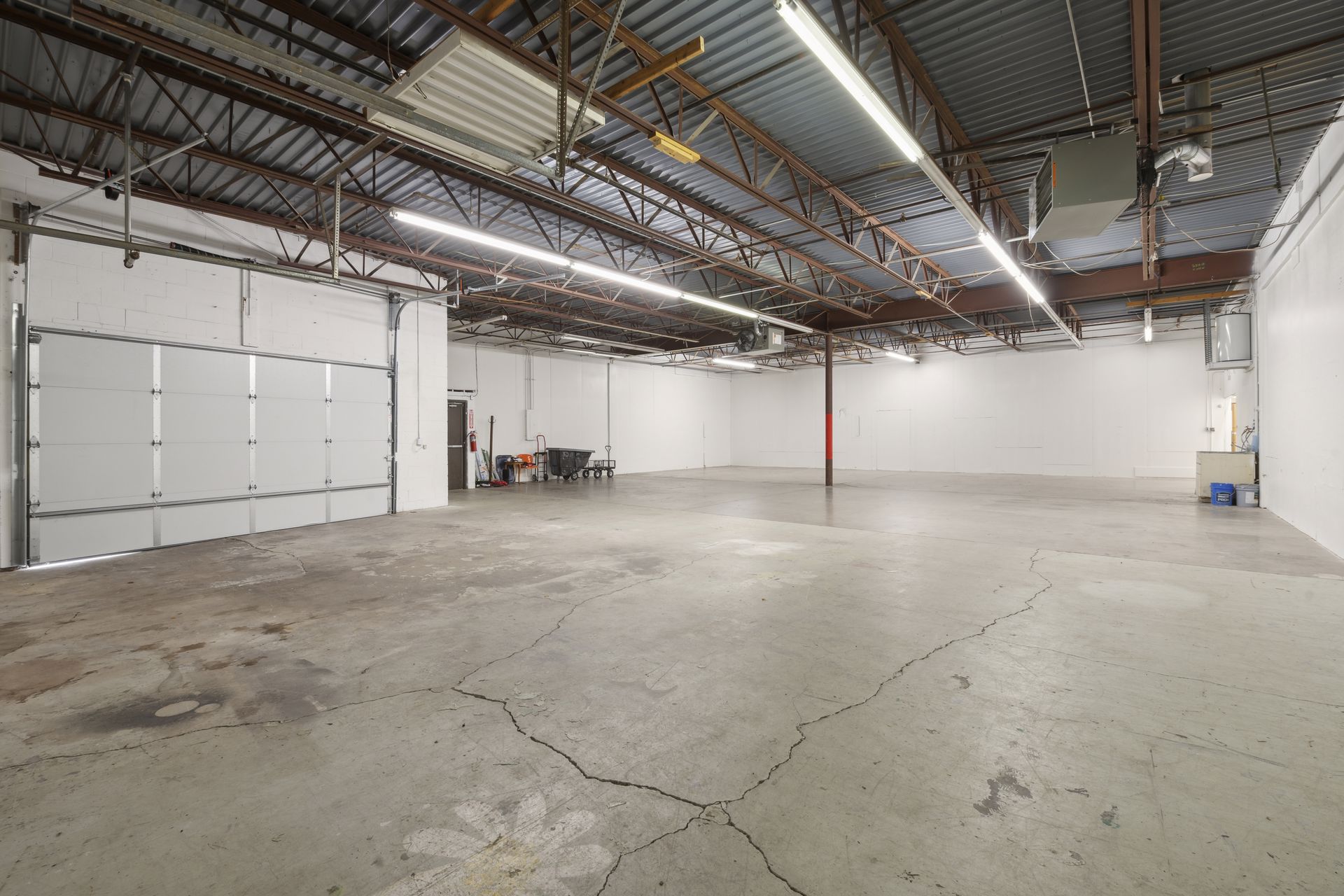 Warehouse bay with a white overhead door and a suspended gas unit heater