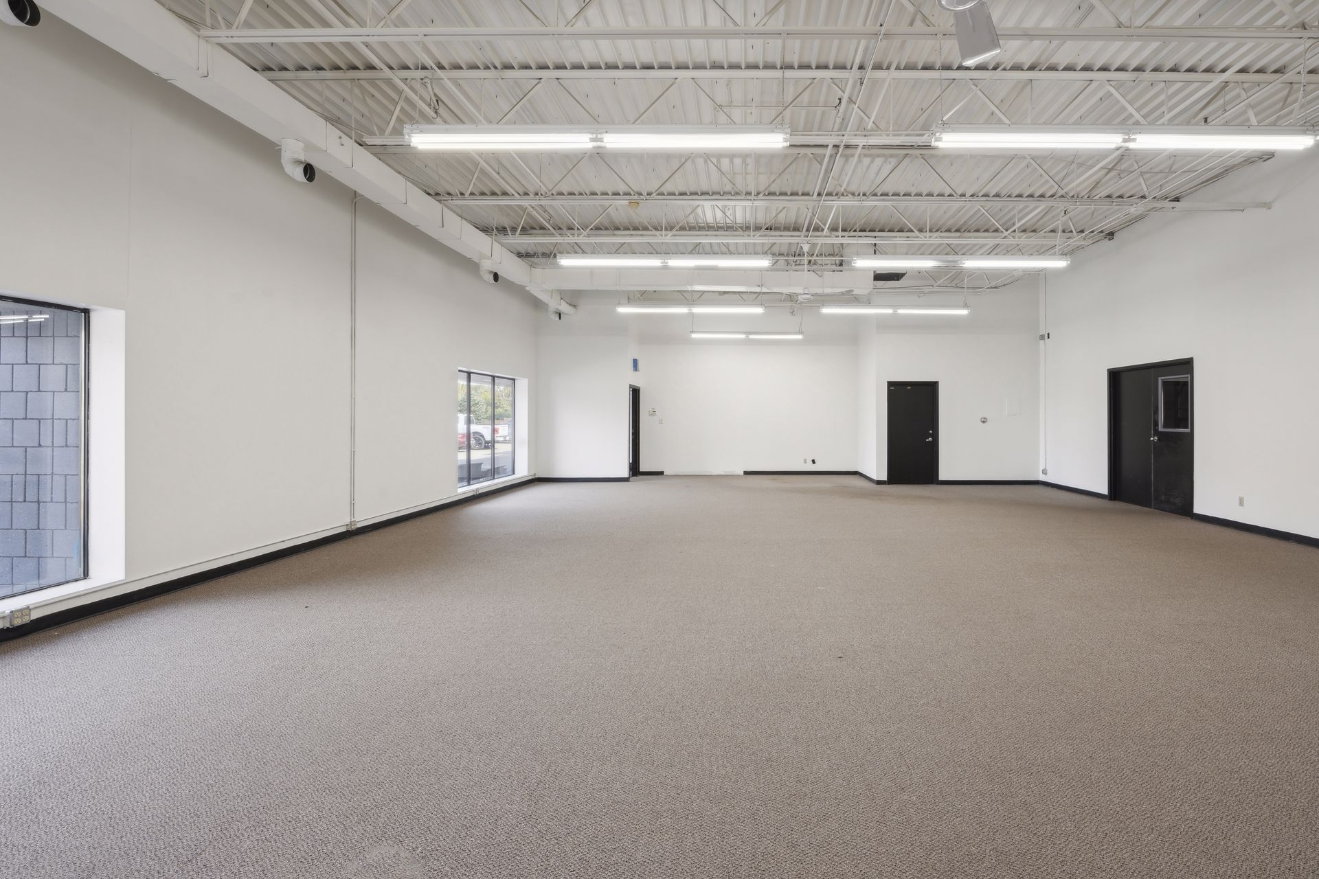 Large open carpeted suite with a glass block window and doors on the far wall