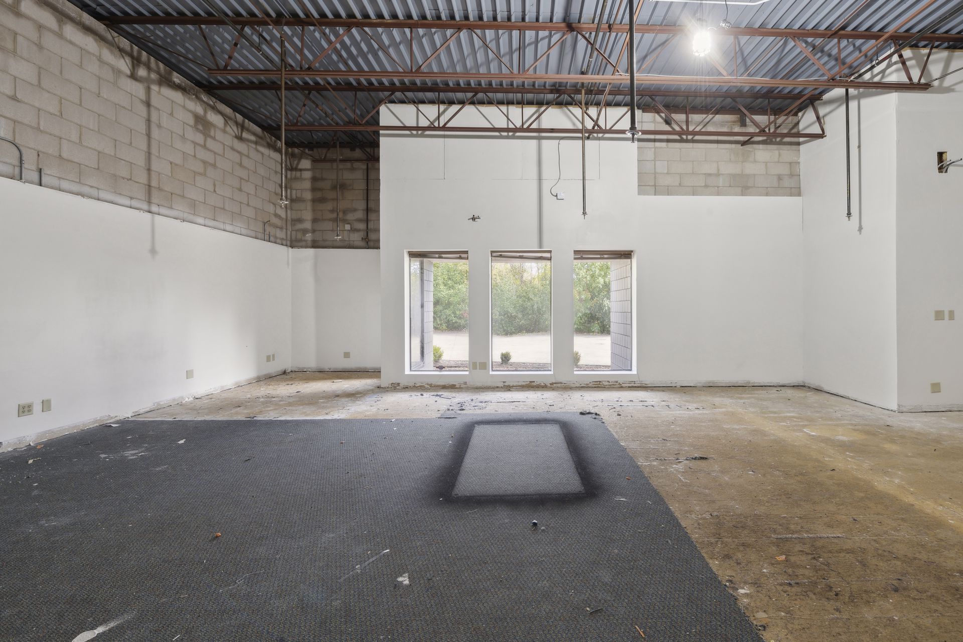 Interior space under renovation looking toward a three-panel storefront window