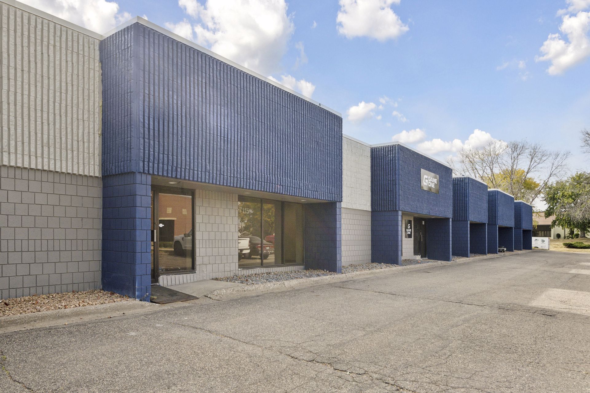 Blue-clad storefront elevation with a glazed tenant entrance and a small wall-mounted sign