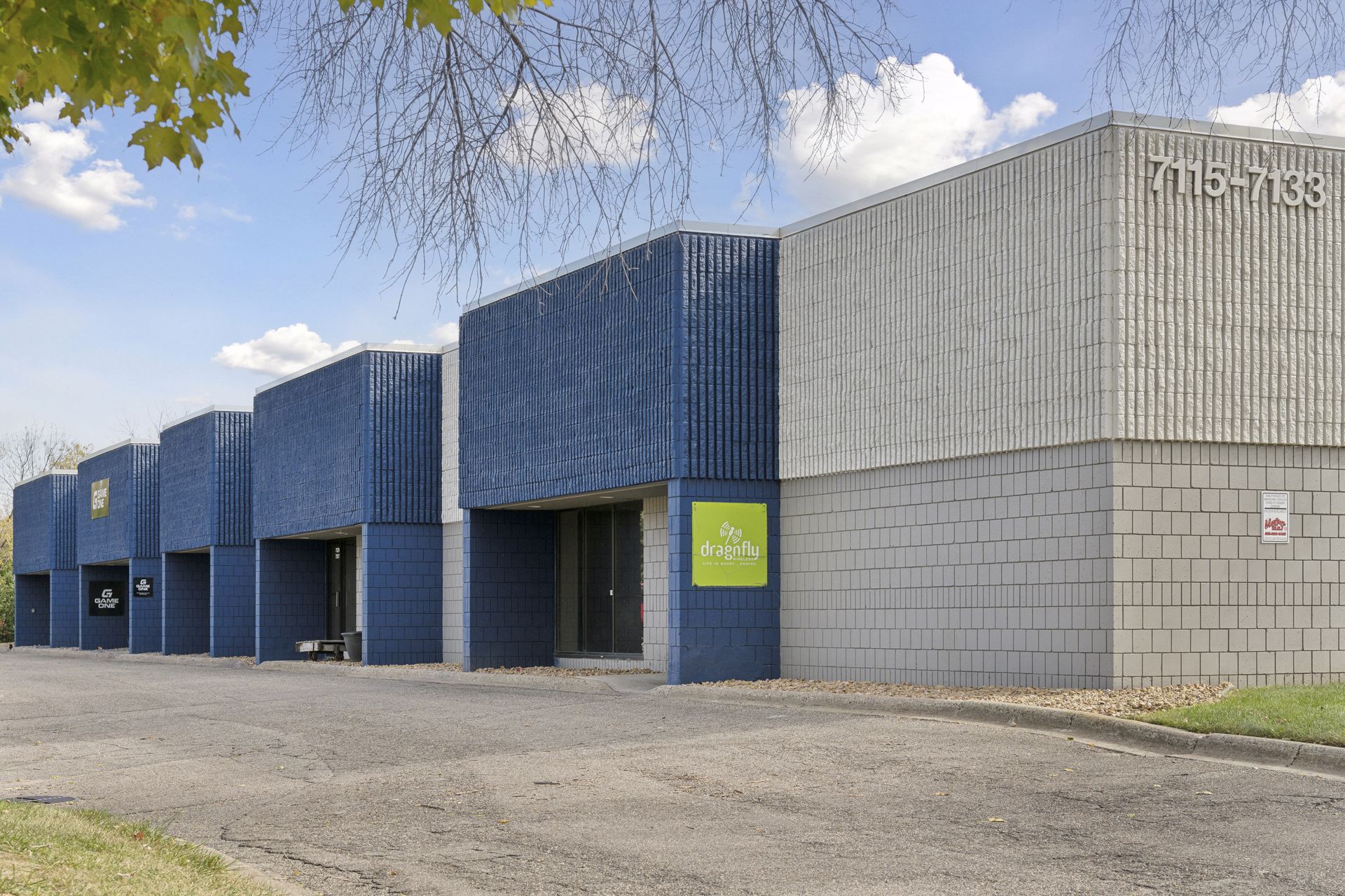 Blue projecting entry bays with a green square tenant sign above one recessed doorway