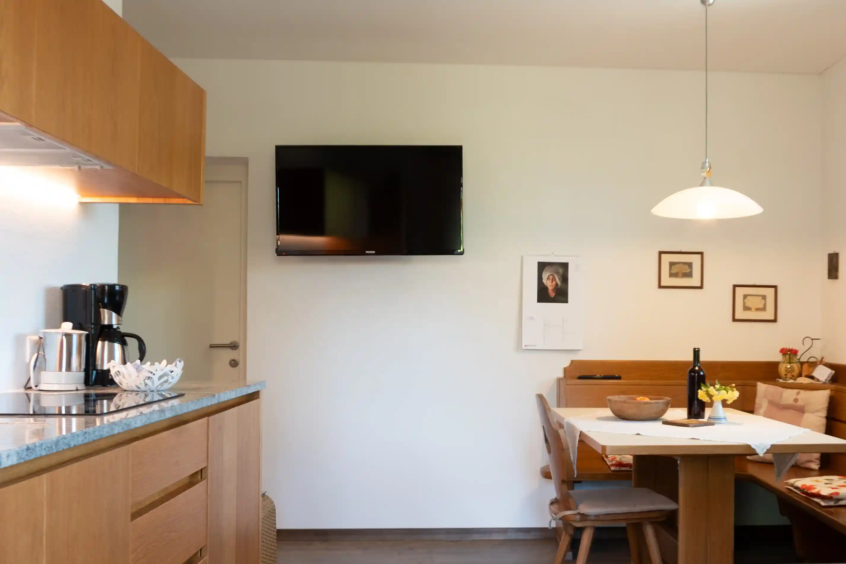 Helle Wohnküche mit Esstisch und TV im Appartment Latemar