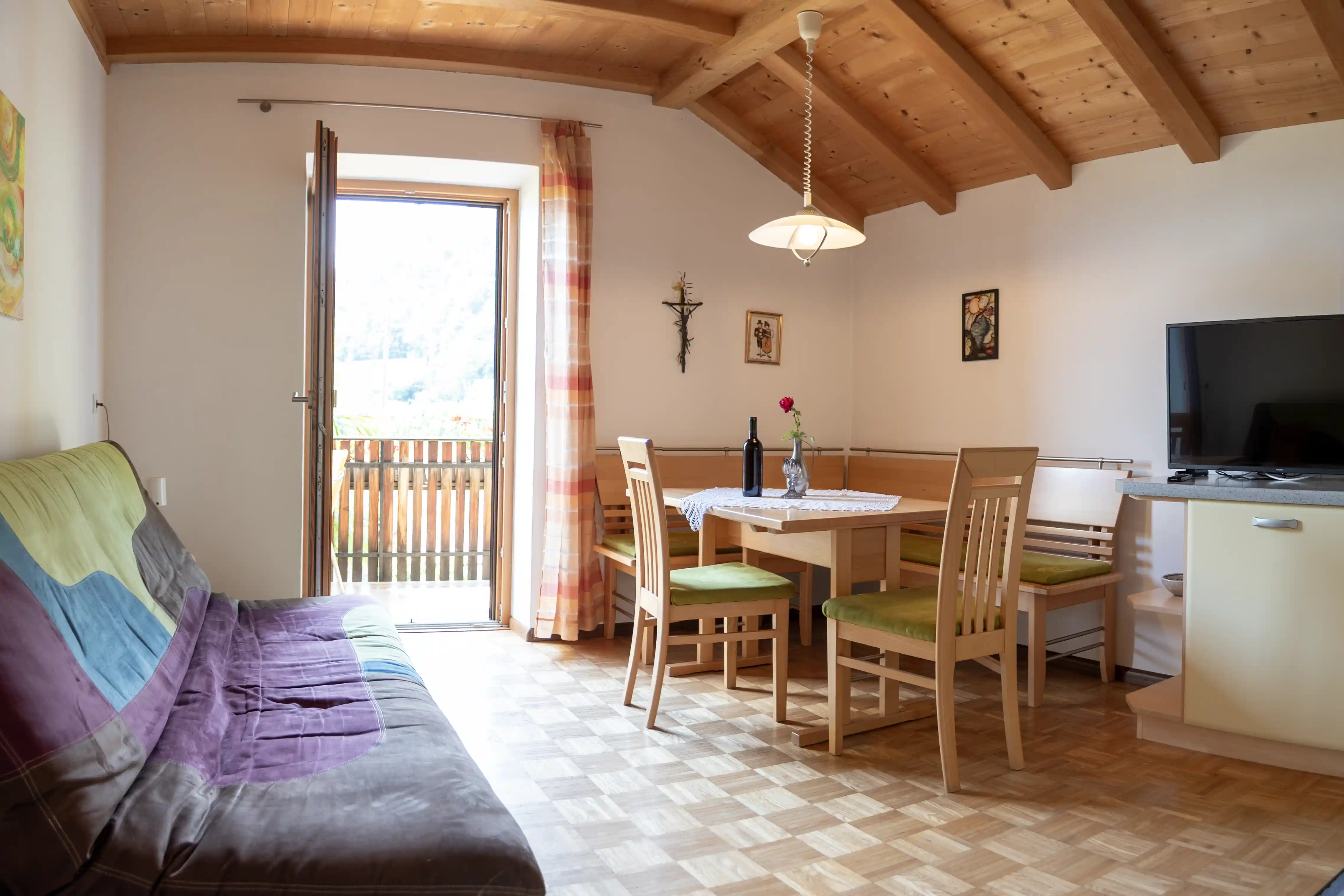 Wohnküche mit Schlafsofa, Esstisch und Balkontür im Appartment Weisshorn
