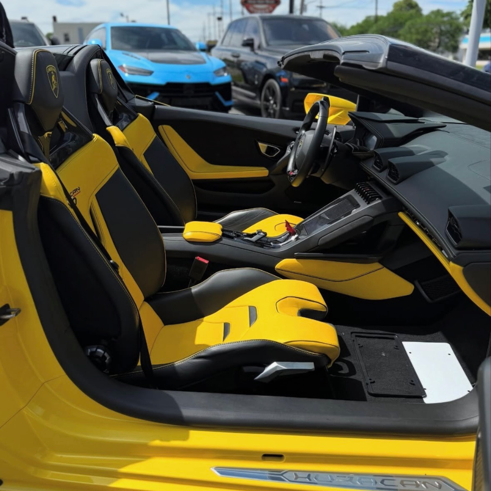 Yellow and black leather interior of a Lamborghini Huracan convertible with visible seats and dashboard.
