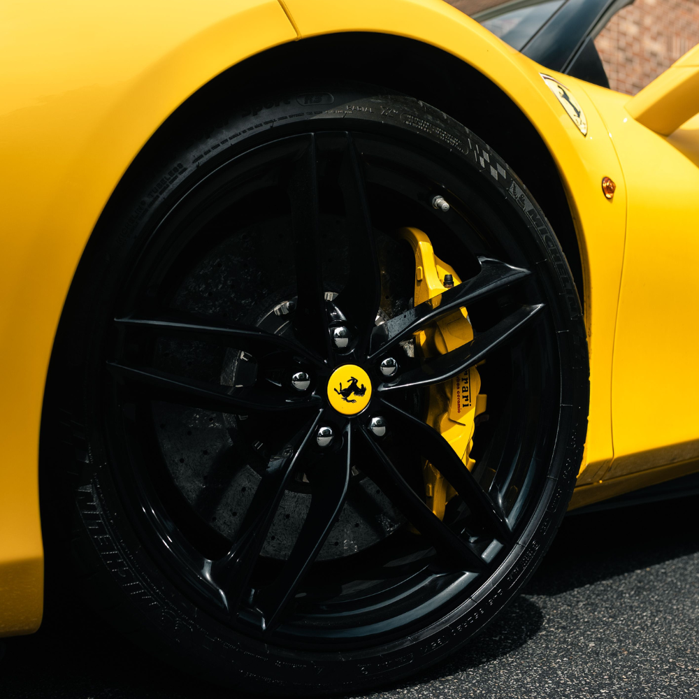 Close-up of a yellow Ferrari sports car tire with a black rim and yellow brake caliper.