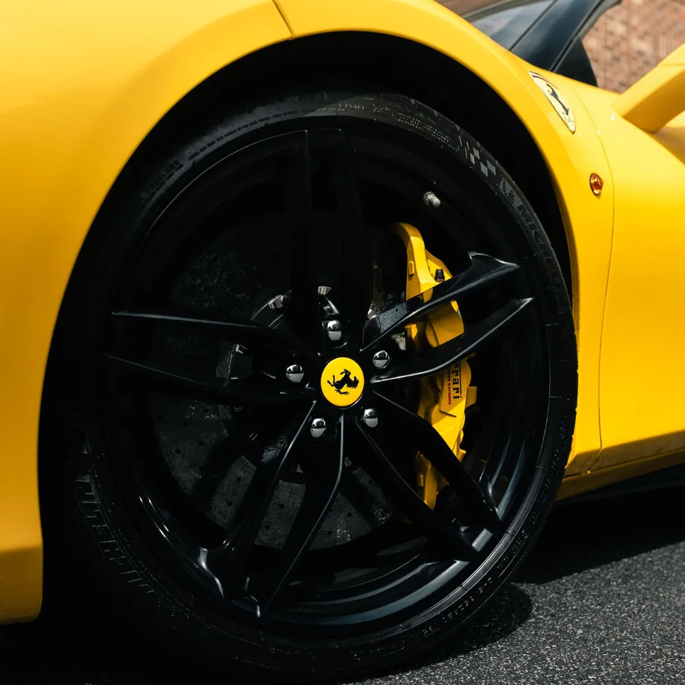 Black wheel and yellow brake caliper on a yellow Ferrari 488 Spyder