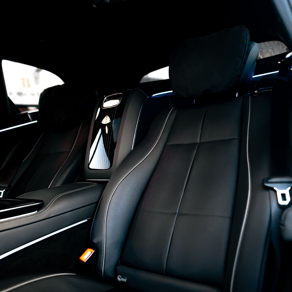 Close-up of black leather luxury car seats with cushioned headrests and detailed stitching.