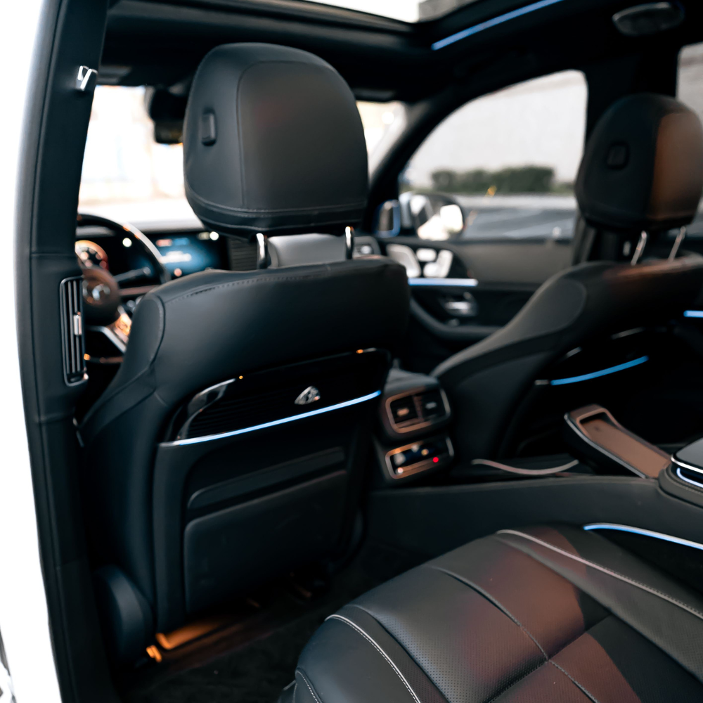 Interior of a luxury car showing black leather seats, front dashboard, and rear passenger area.