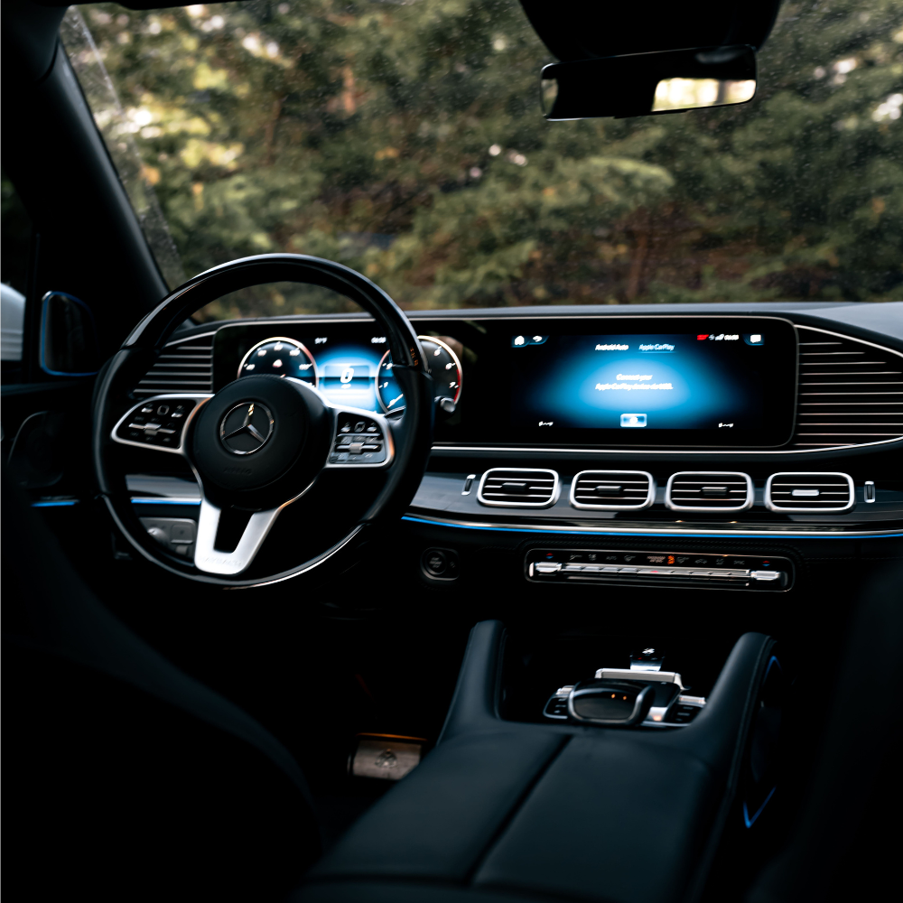 Interior of a Mercedes car showing steering wheel, digital dashboard, and center console touchscreen.
