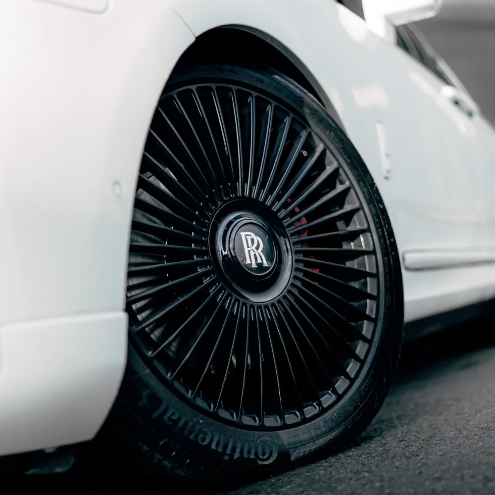 Black multi-spoke wheel with Rolls-Royce center cap on a white Cullinan
