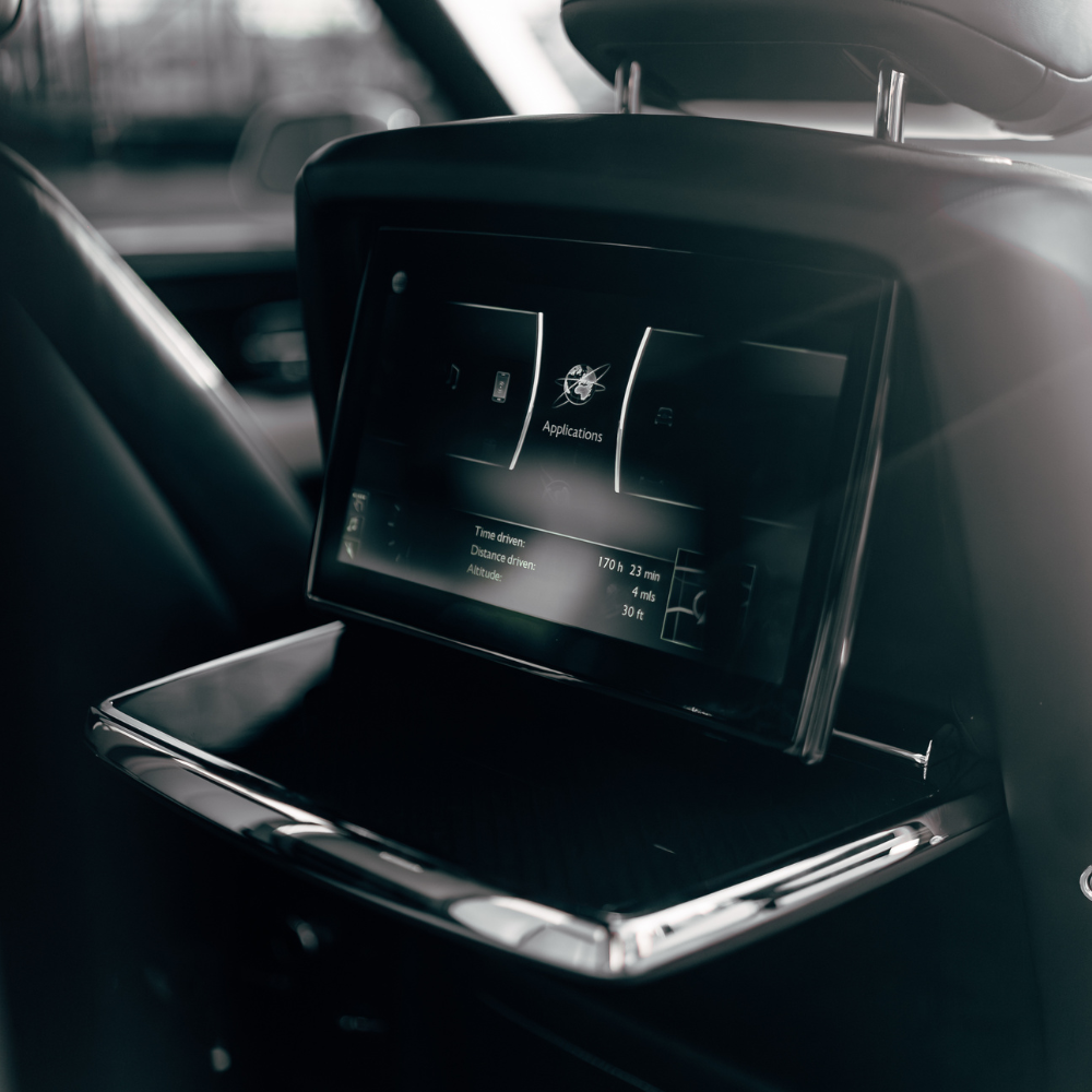 Car seat back with an integrated touchscreen displaying applications and driving stats.