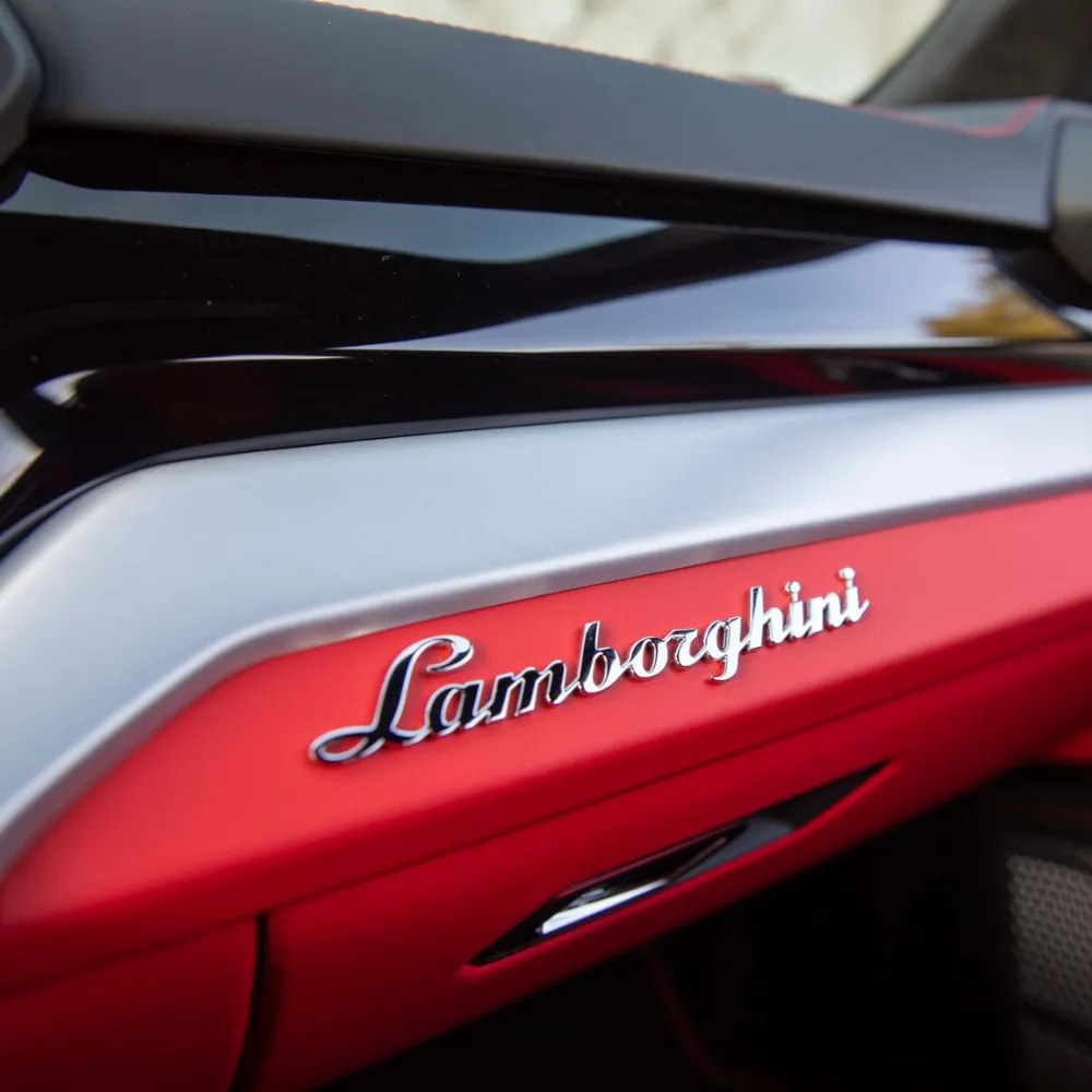 Lamborghini script badge on the red dashboard trim of a Urus