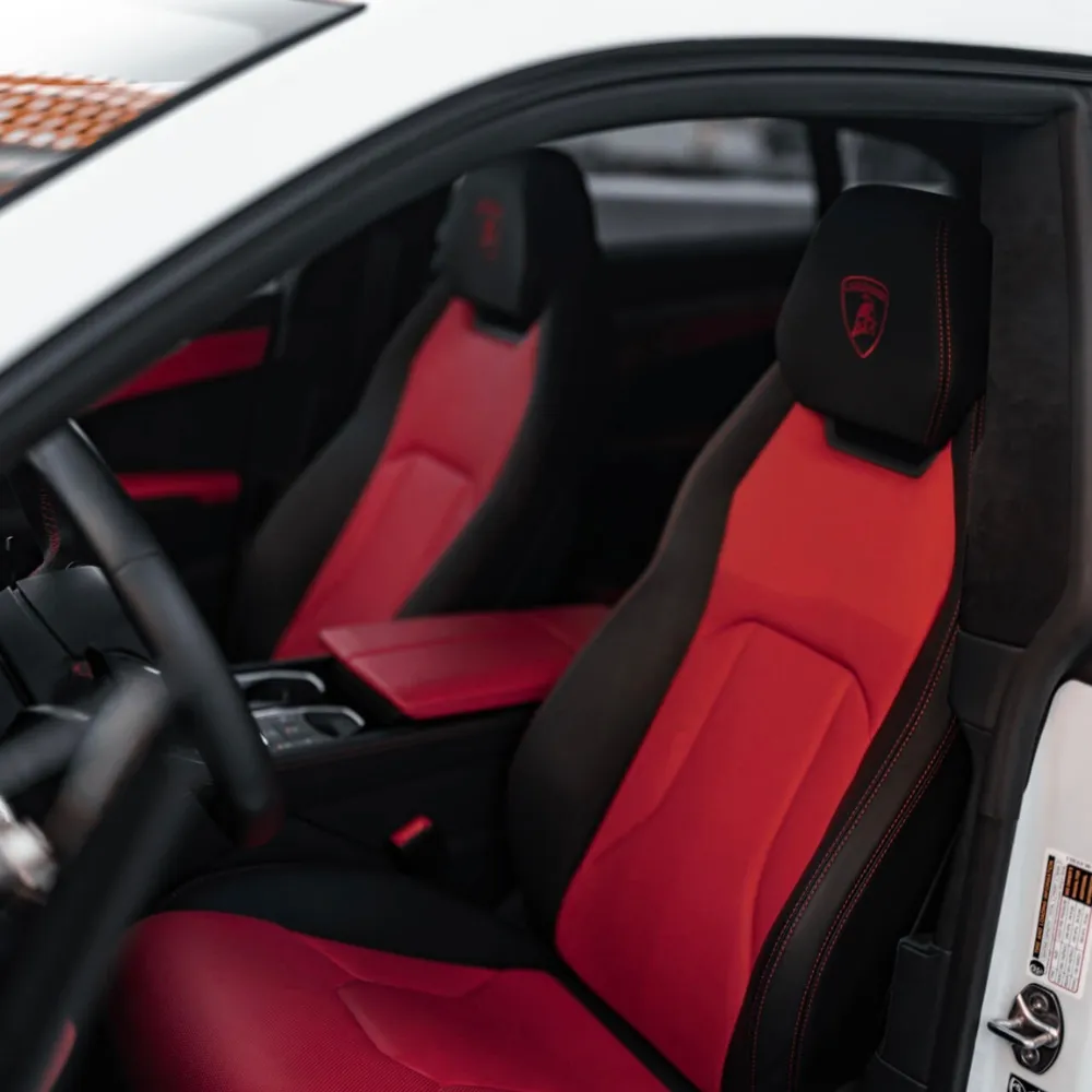 Red and black leather front seats with Lamborghini crest in a Urus