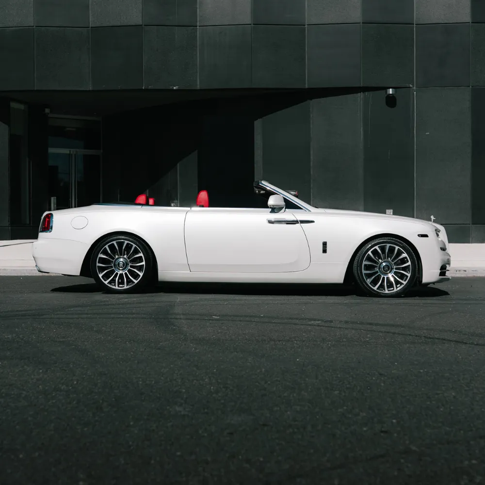 Side view of a white Rolls-Royce Dawn with the top down and red seats