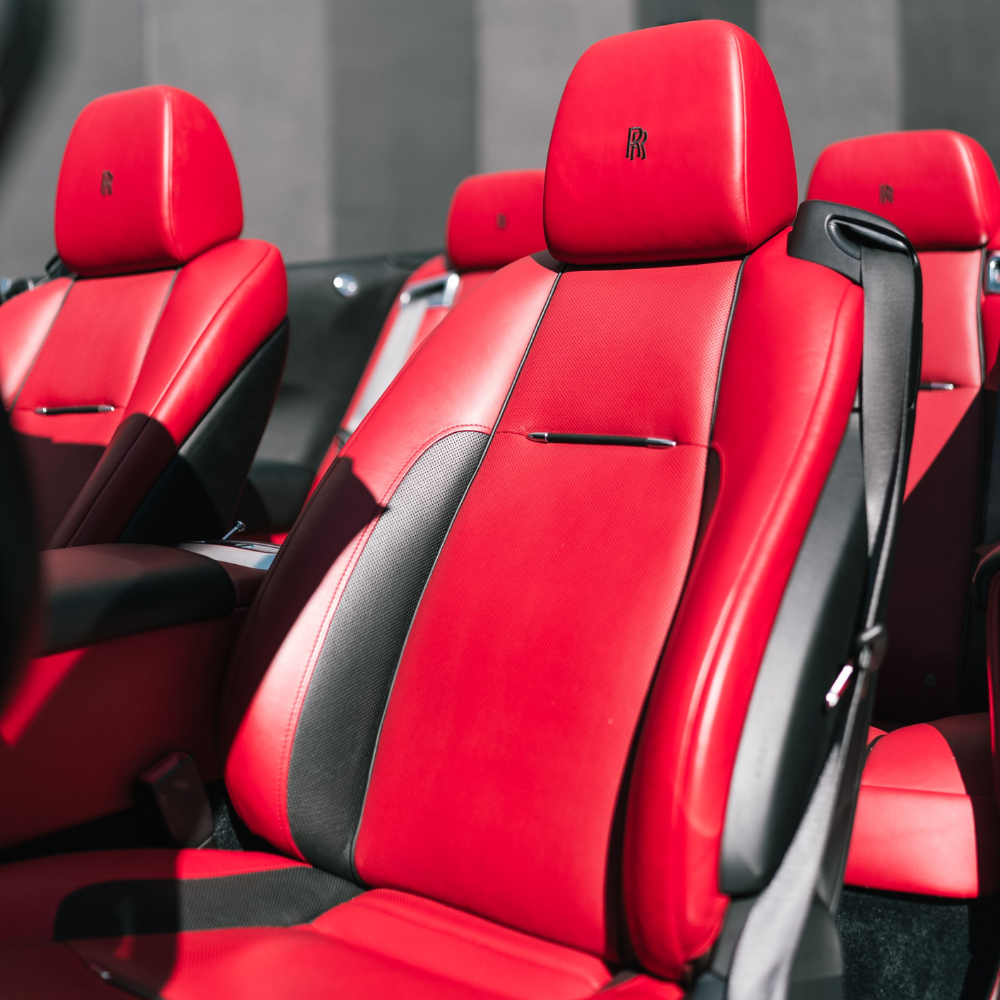 Close-up of red leather car seats with Rolls-Royce logos on the headrests.