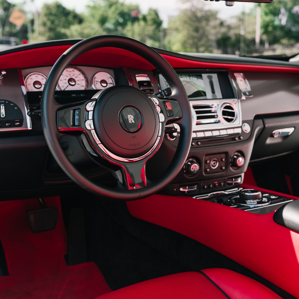Luxury car interior showcasing black leather steering wheel and vibrant red leather seats and dashboard.
