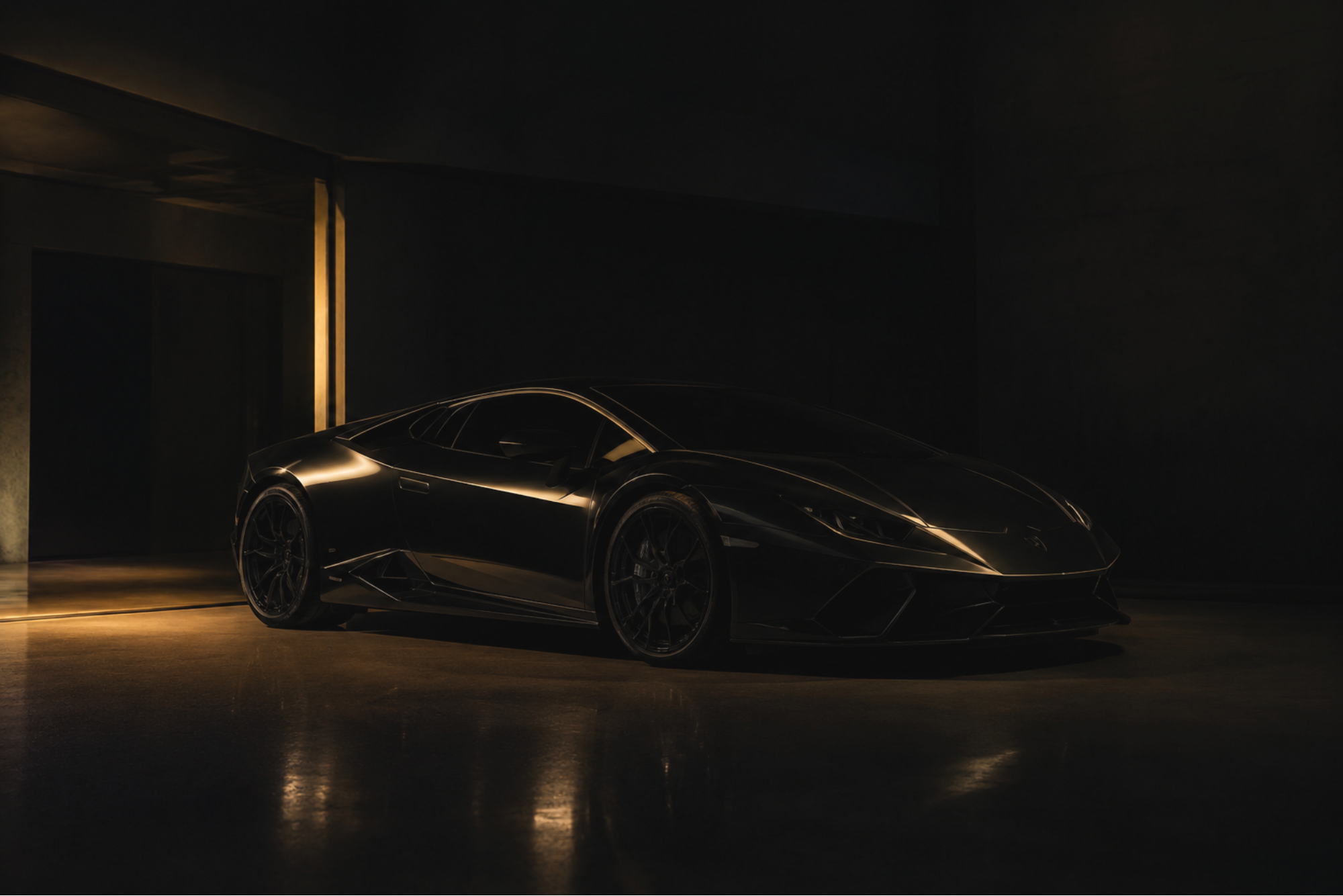 Black luxury sports car parked indoors with warm light reflections on its sleek surface.