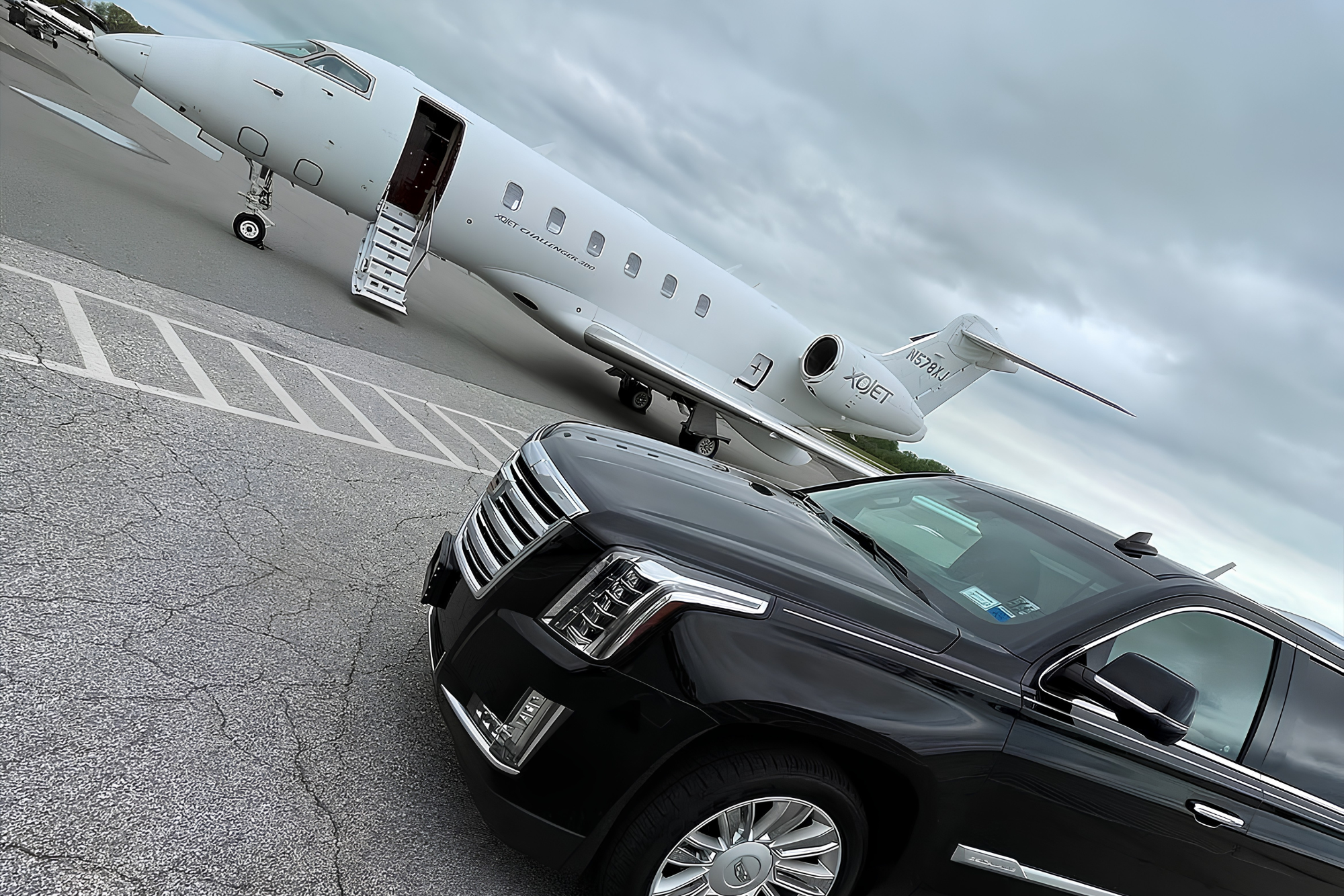 Escalade pulling up to a private airport with a private jet in the background