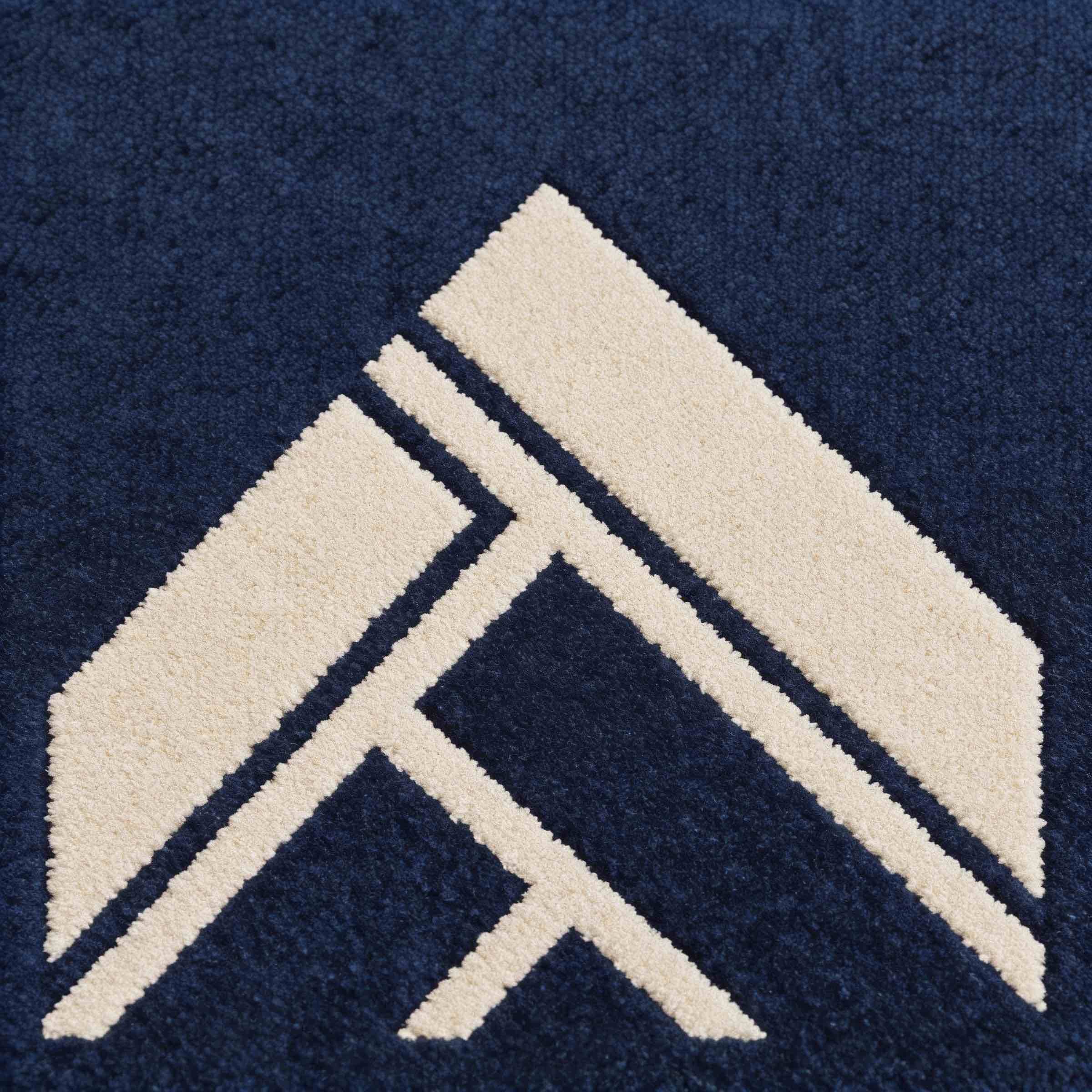 Close-up of a navy carpet featuring a geometric pattern with cream-colored shapes forming an angular design.