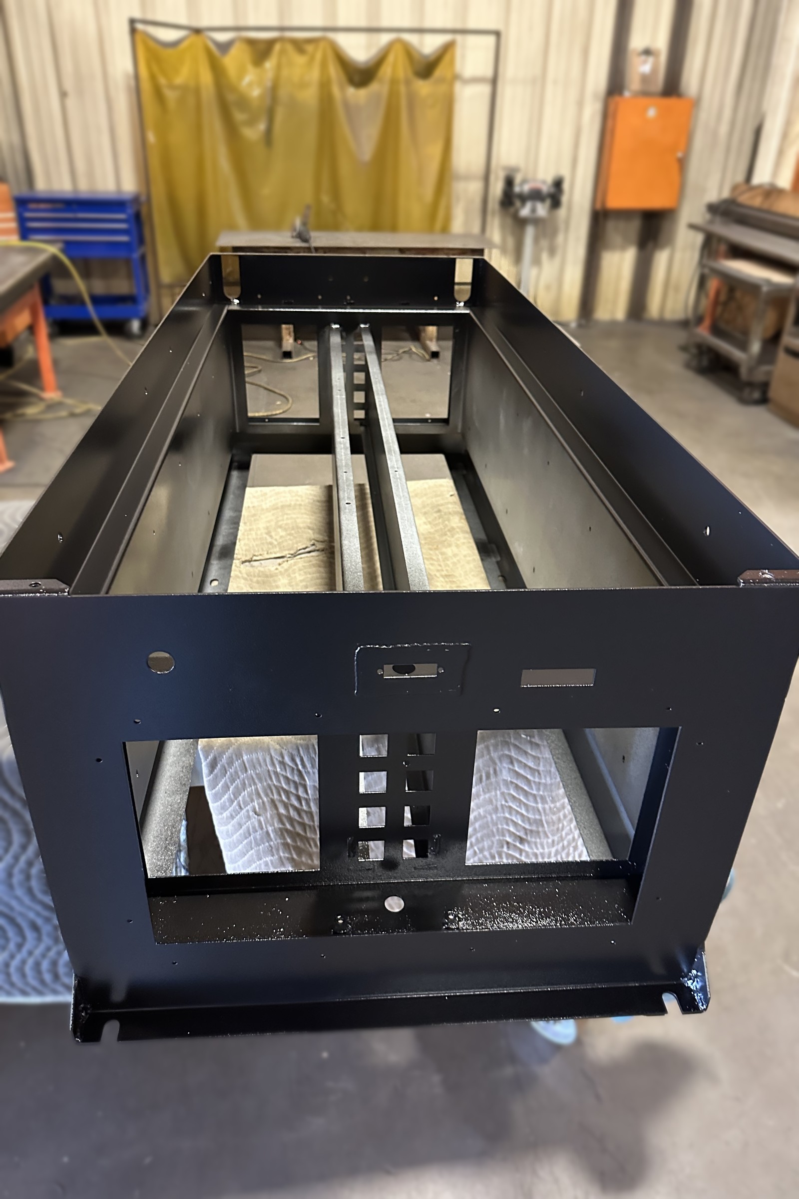 Black painted welded machine base with an access opening.