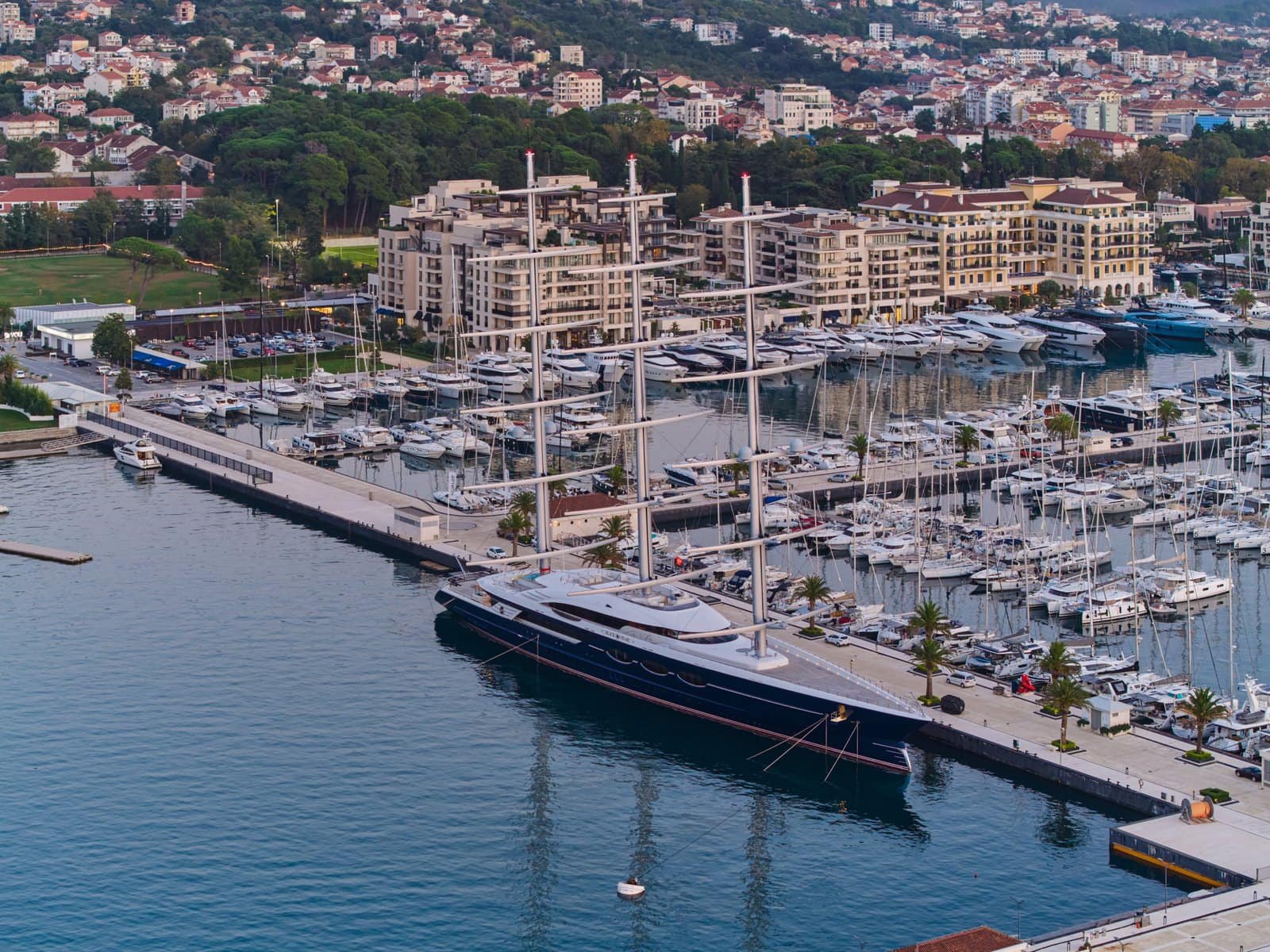 Luxury yacht docked at a marina with modern residential buildings in the background.