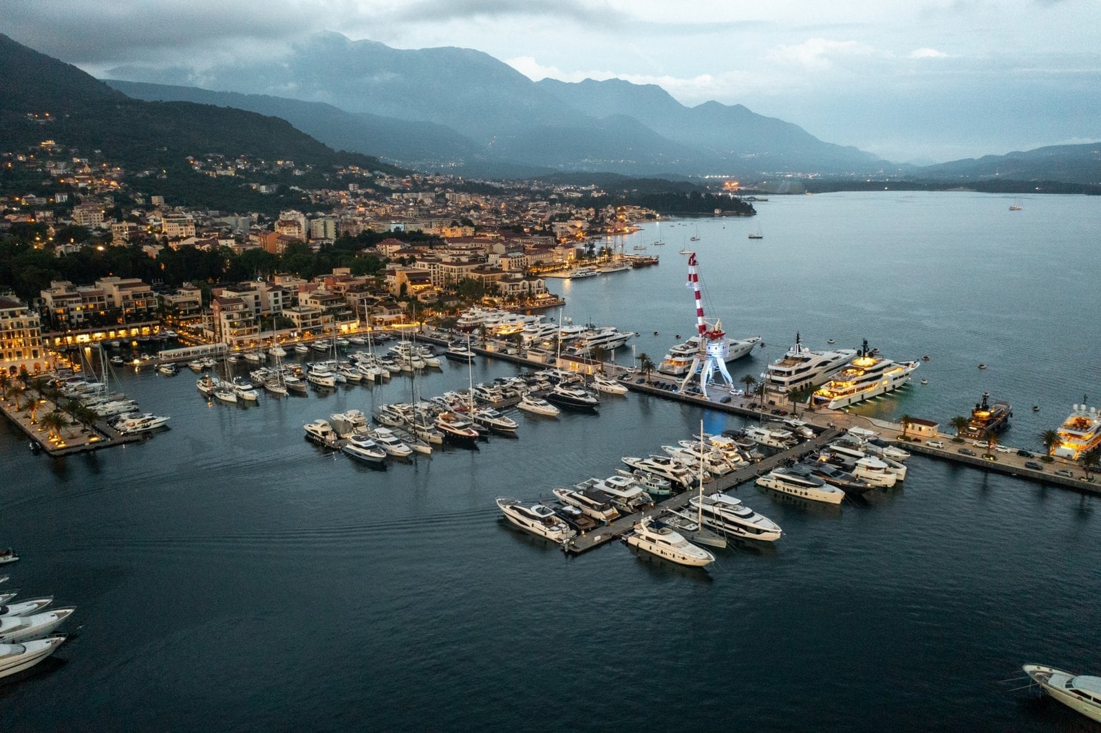 Marina with yachts and boats in Lake Como, Italy, surrounded by scenic mountains and a charming town.