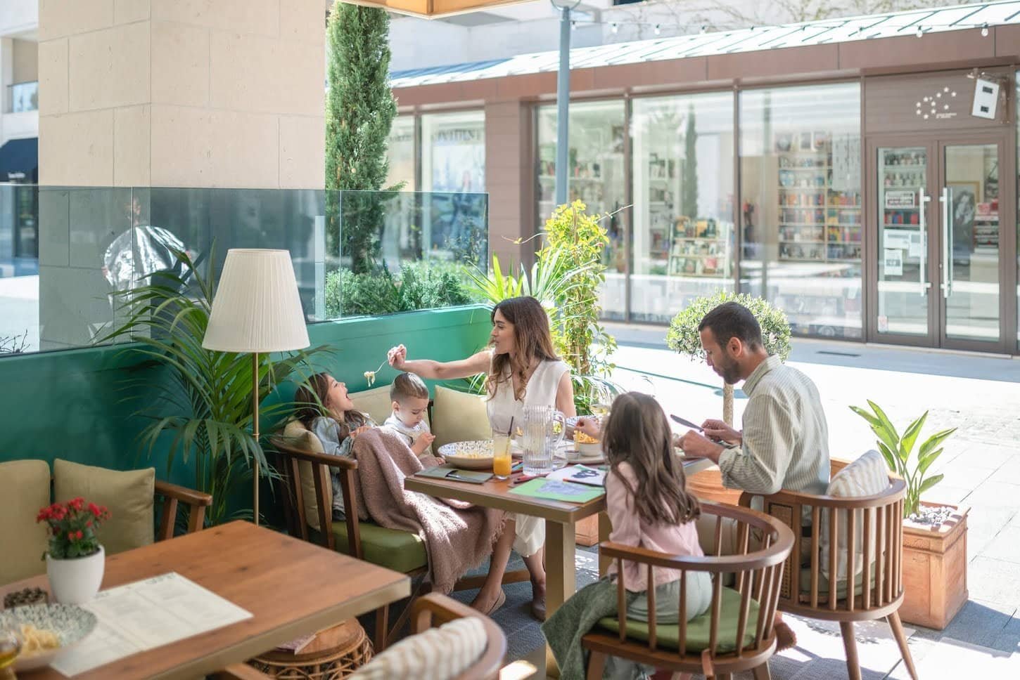Family enjoying meal together in a cozy, stylish cafe setting.